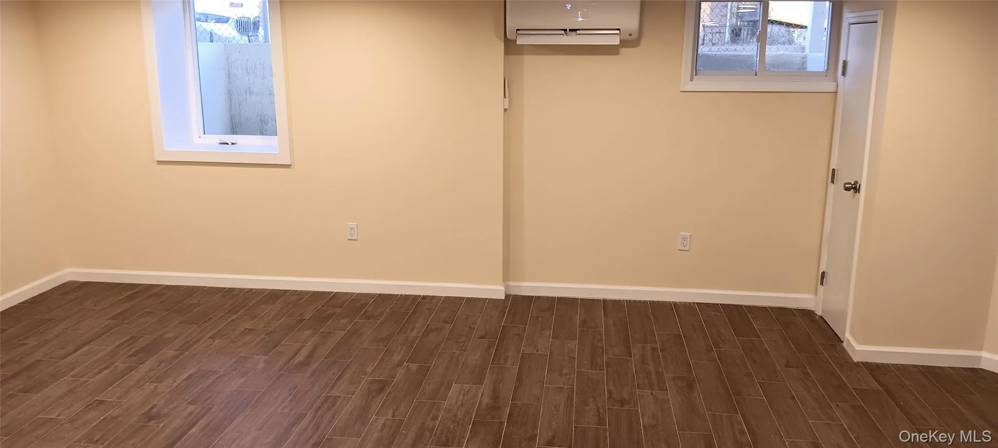 Below grade area featuring wood finish floors and an AC wall unit Below grade area featuring wood finish floors and an AC wall unit