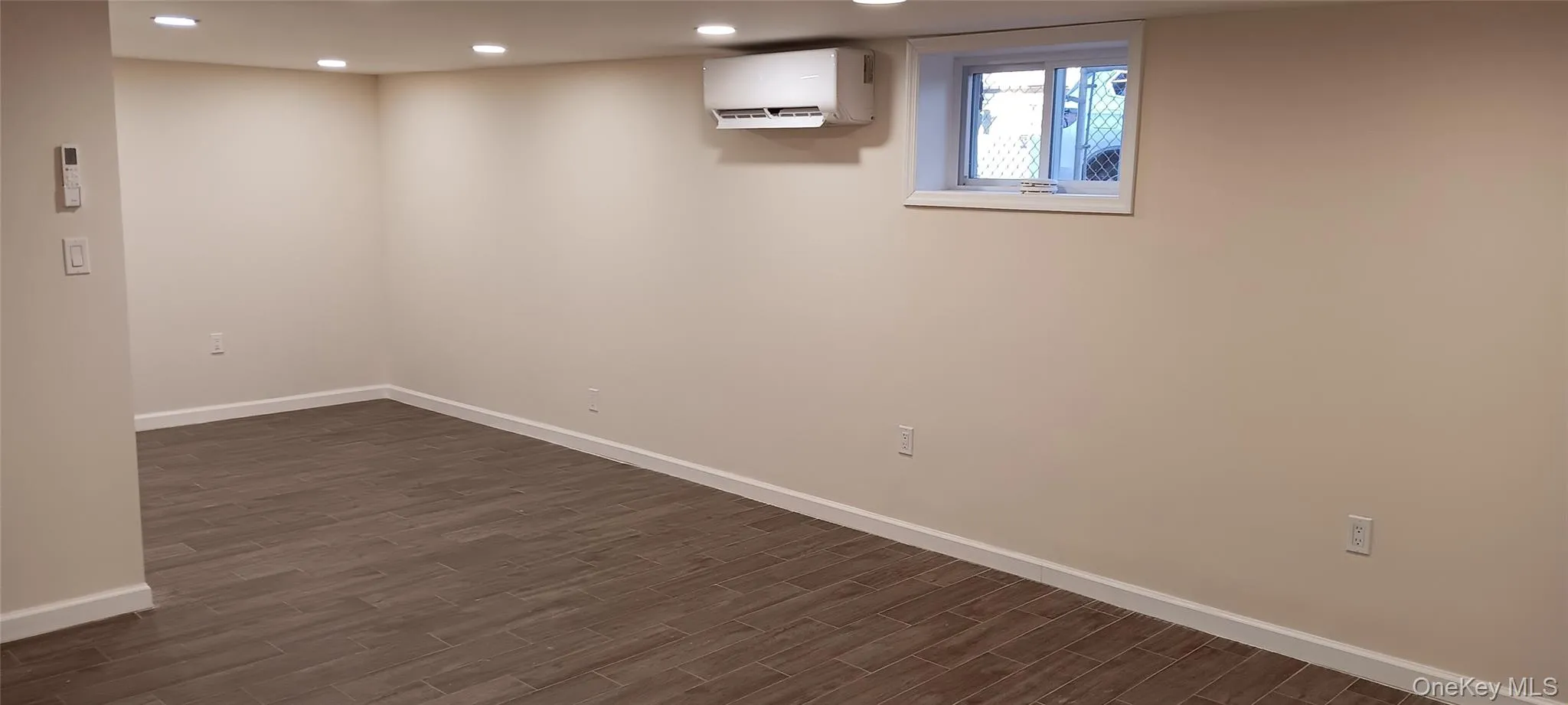 Basement with recessed lighting, a wall mounted air conditioner, and dark wood finished floors Basement with recessed lighting, a wall mounted air conditioner, and dark wood finished floors