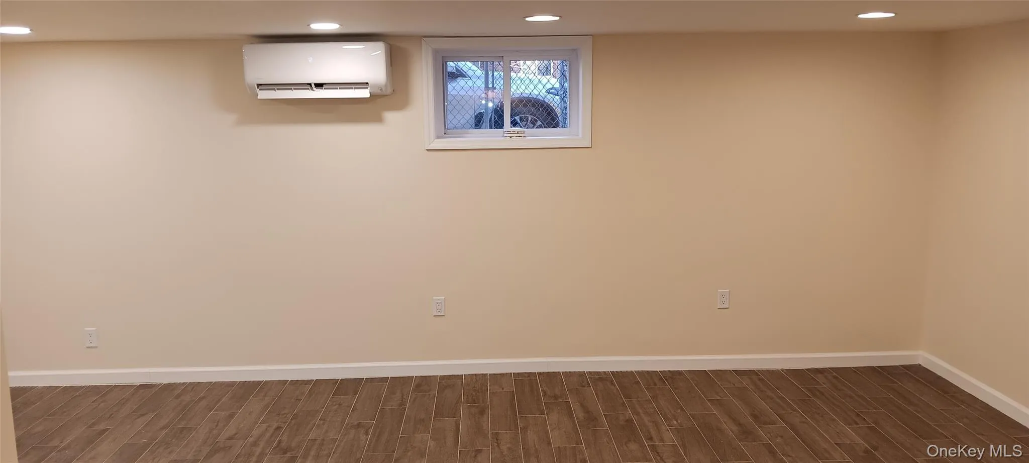 Basement featuring wood finish floors, recessed lighting, and a wall mounted air conditioner Basement featuring wood finish floors, recessed lighting, and a wall mounted air conditioner