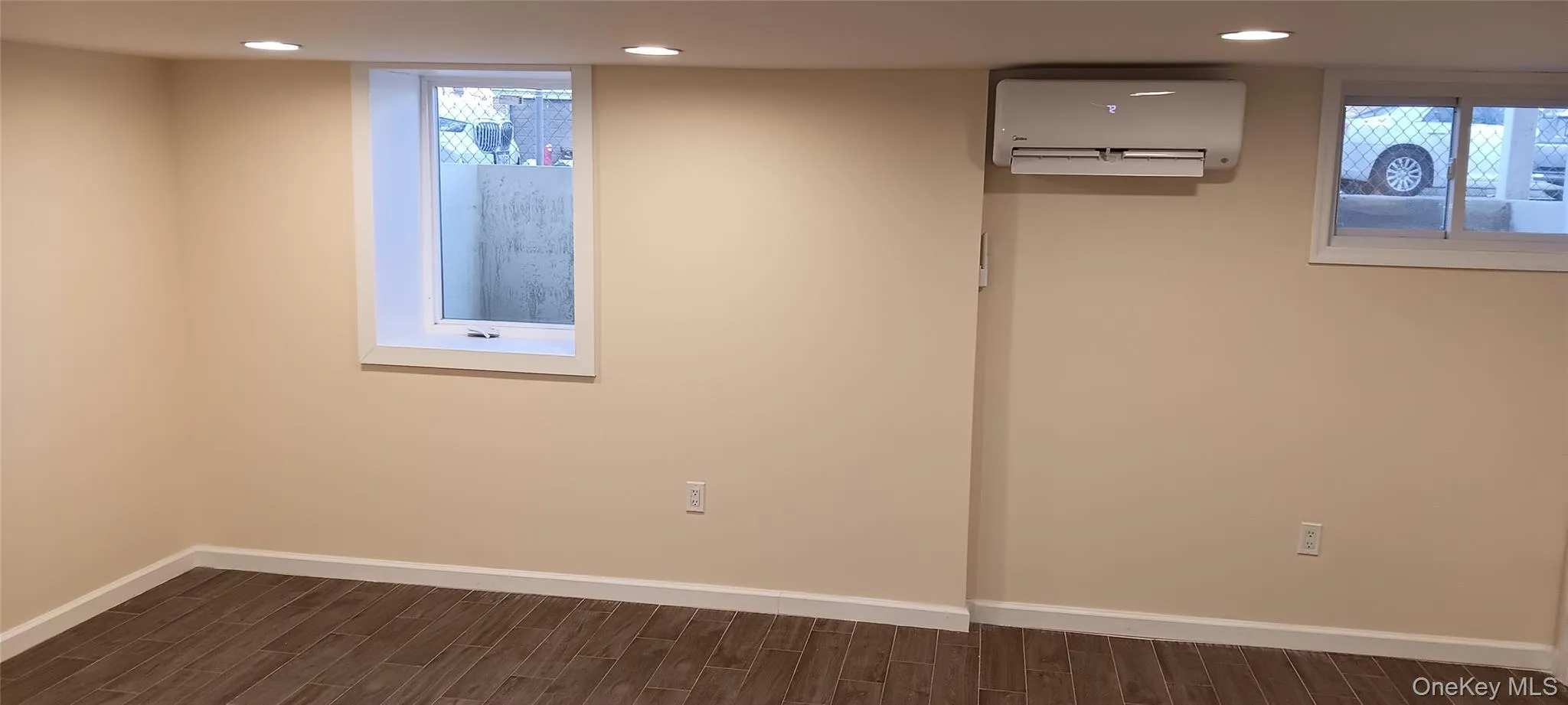 Basement featuring wood tiled floors, a wall unit AC, and recessed lighting Basement featuring wood tiled floors, a wall unit AC, and recessed lighting