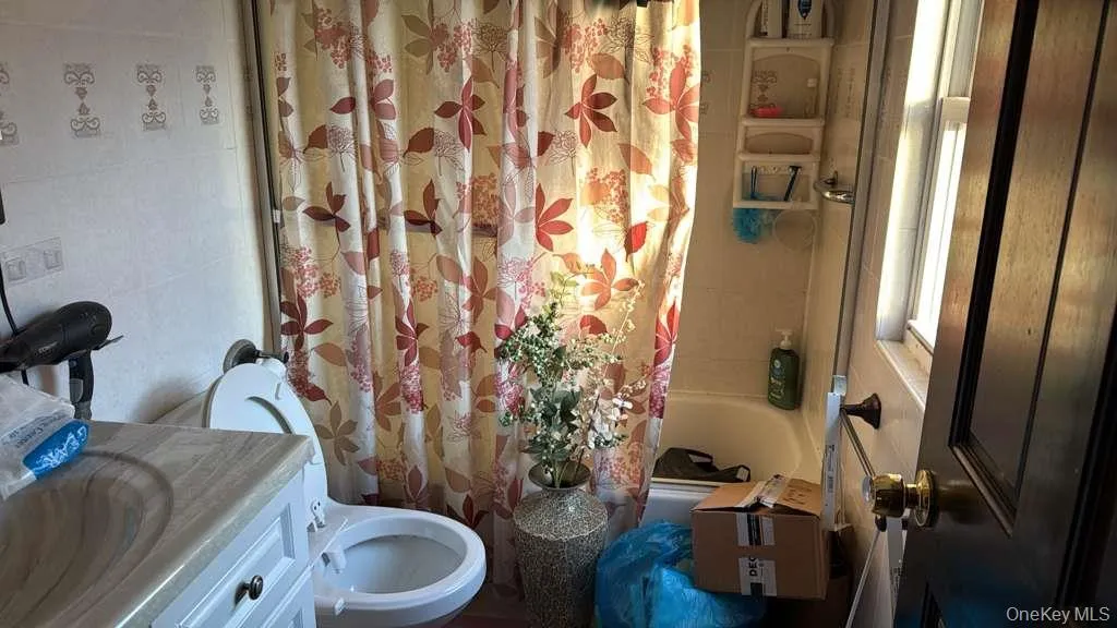 Full bath with shower / bath combo with shower curtain, vanity, and tile walls Full bath with shower / bath combo with shower curtain, vanity, and tile walls