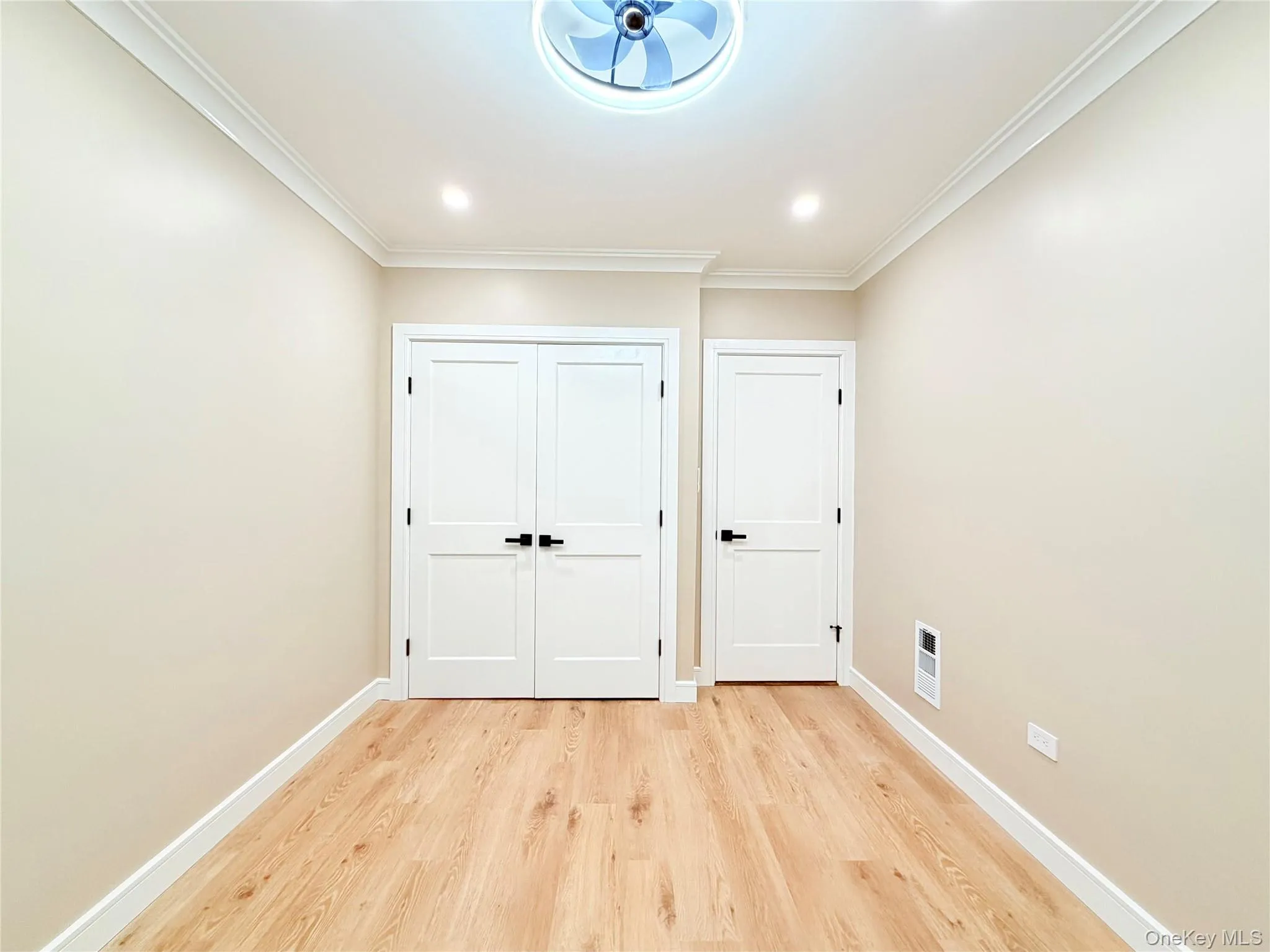 Unfurnished bedroom with light wood-style floors, ornamental molding, and a closet Unfurnished bedroom with light wood-style floors, ornamental molding, and a closet