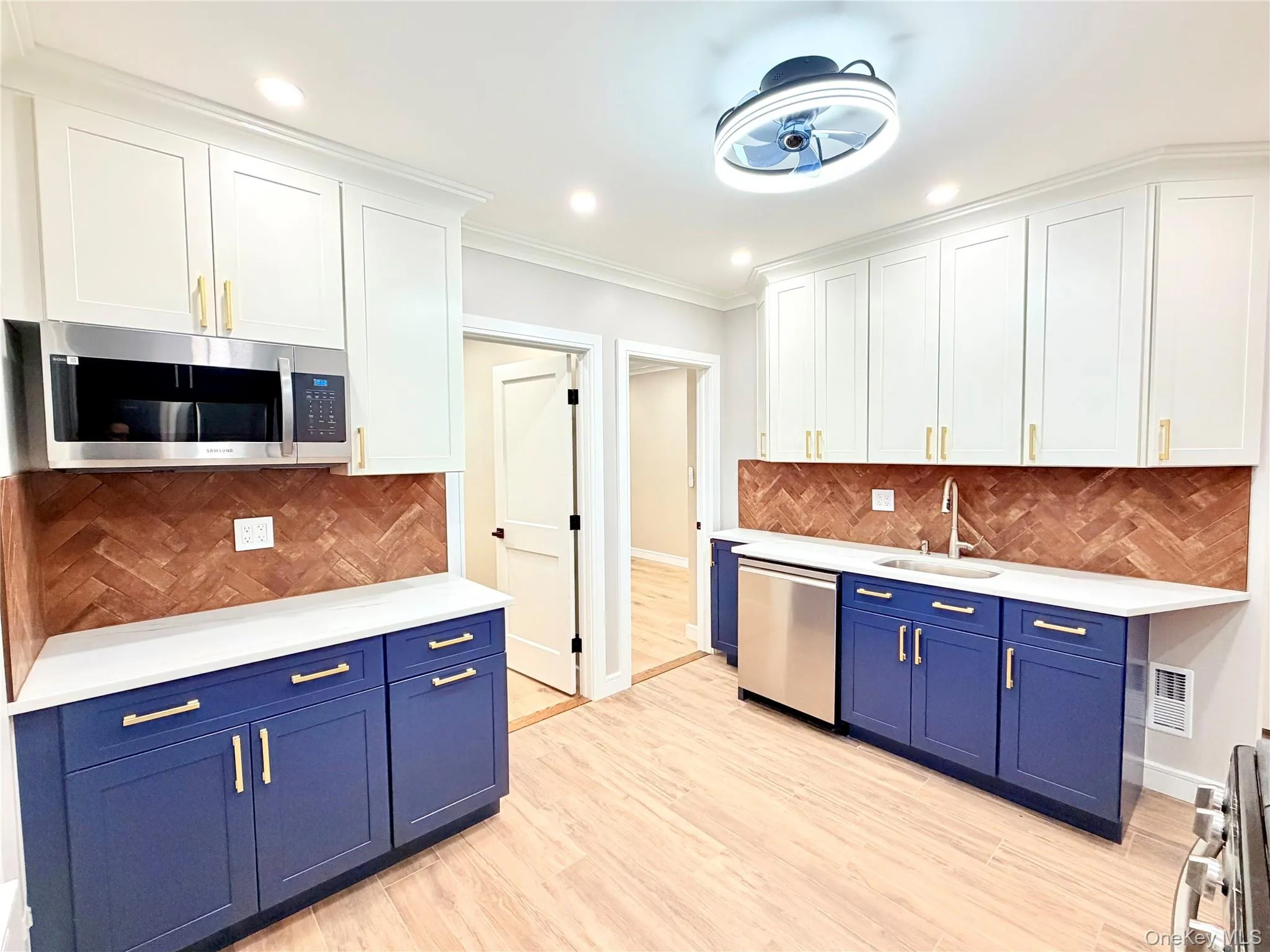 Kitchen with blue cabinets, tasteful backsplash, white cabinets, stainless steel appliances, and ornamental molding Kitchen with blue cabinets, tasteful backsplash, white cabinets, stainless steel appliances, and ornamental molding