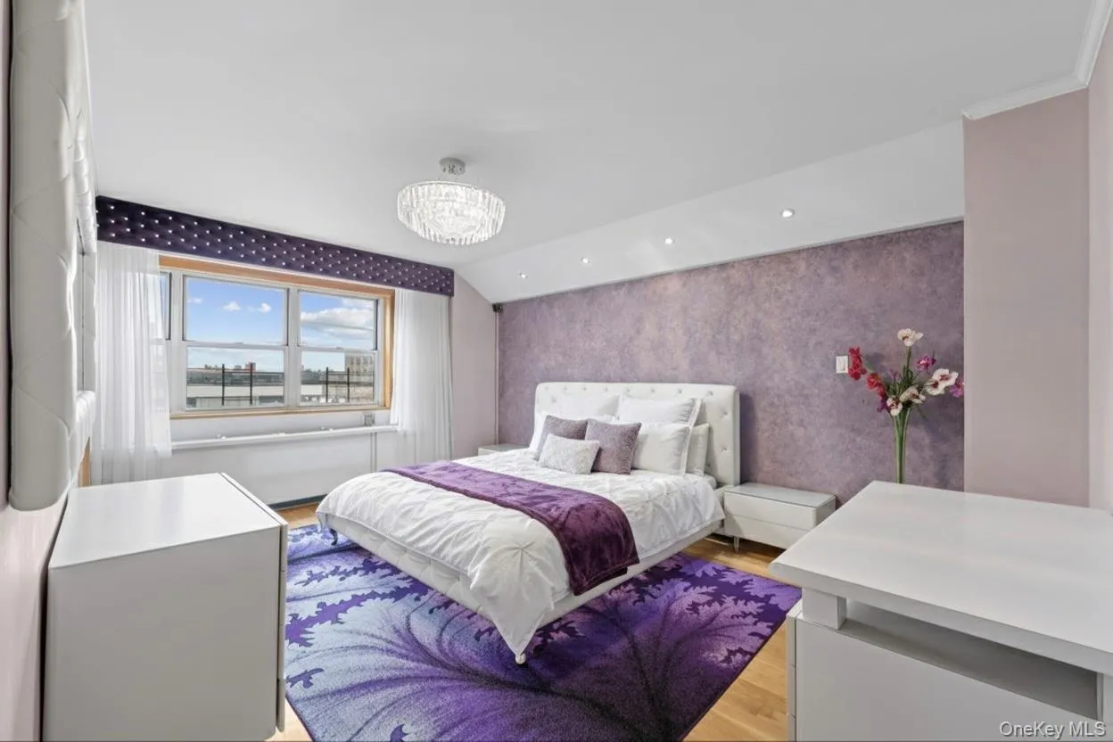 Bedroom featuring wallpapered walls, light wood-style floors, a chandelier, an accent wall, and lofted ceiling Bedroom featuring wallpapered walls, light wood-style floors, a chandelier, an accent wall, and lofted ceiling