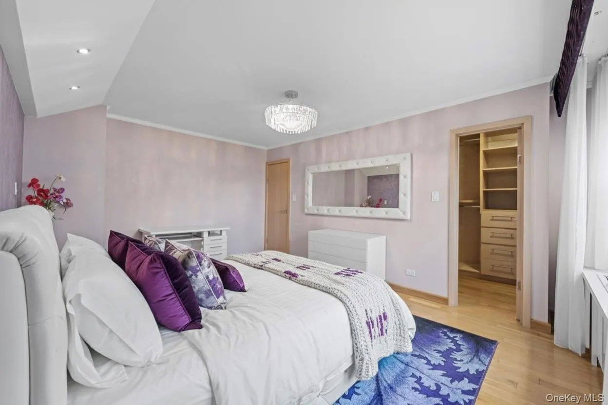 Bedroom with a walk in closet, wood finished floors, a chandelier, recessed lighting, and ornamental molding Bedroom with a walk in closet, wood finished floors, a chandelier, recessed lighting, and ornamental molding