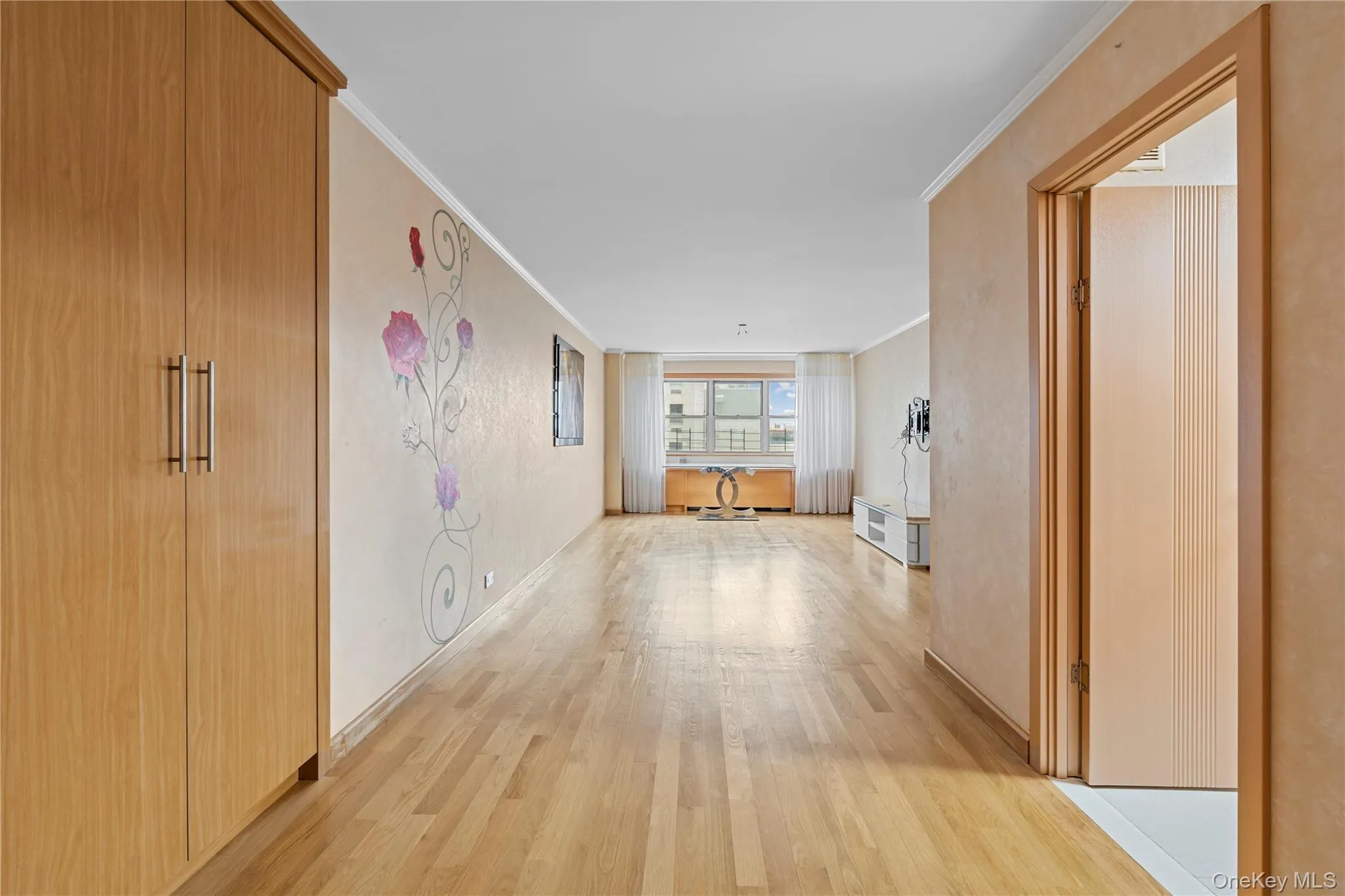 Corridor featuring light wood-style flooring and crown molding Corridor featuring light wood-style flooring and crown molding