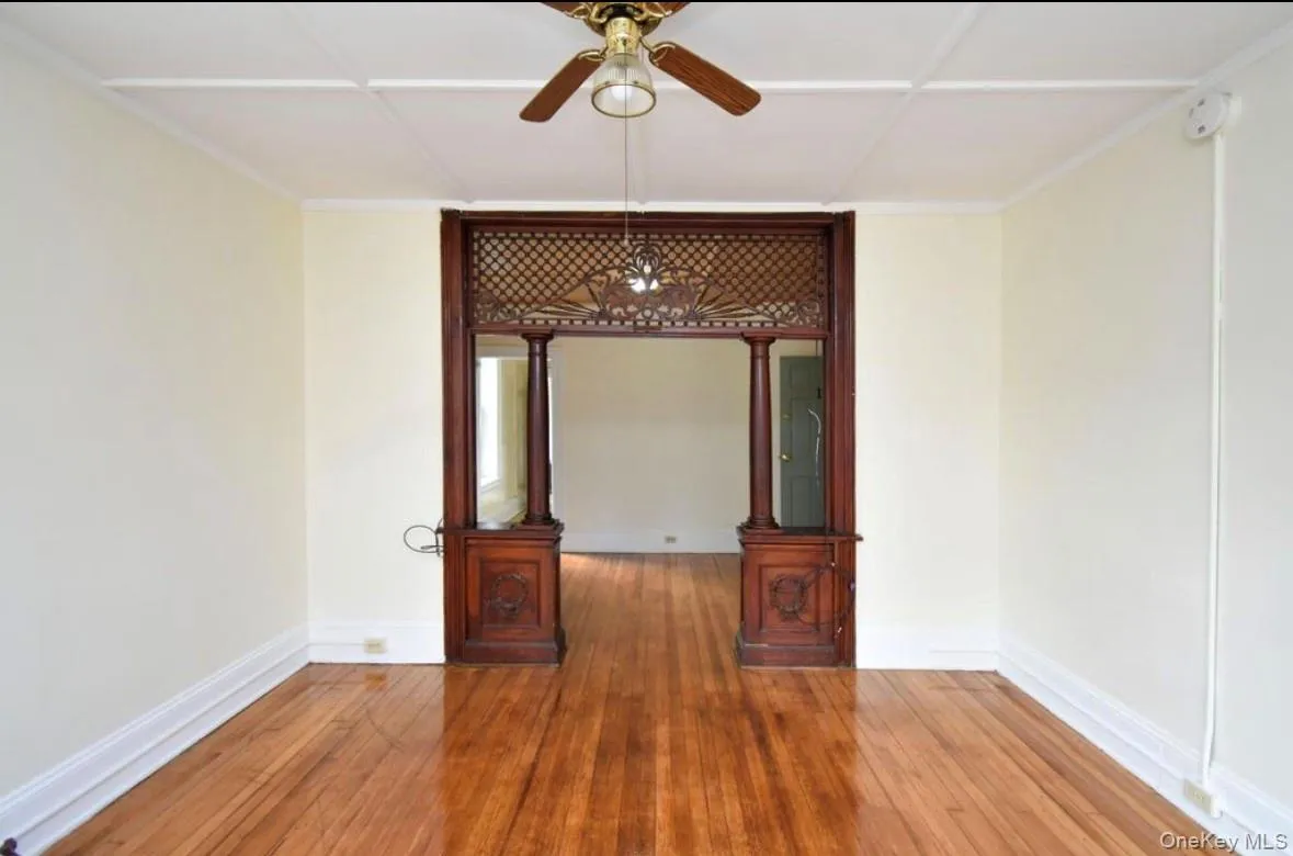 Spare room with hardwood / wood-style flooring, crown molding, a ceiling fan, and a smoke detector Spare room with hardwood / wood-style flooring, crown molding, a ceiling fan, and a smoke detector