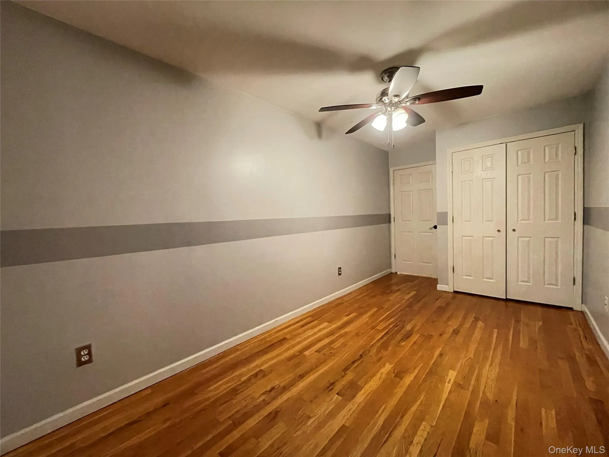 Unfurnished bedroom featuring wood finished floors, a ceiling fan, and a closet Unfurnished bedroom featuring wood finished floors, a ceiling fan, and a closet