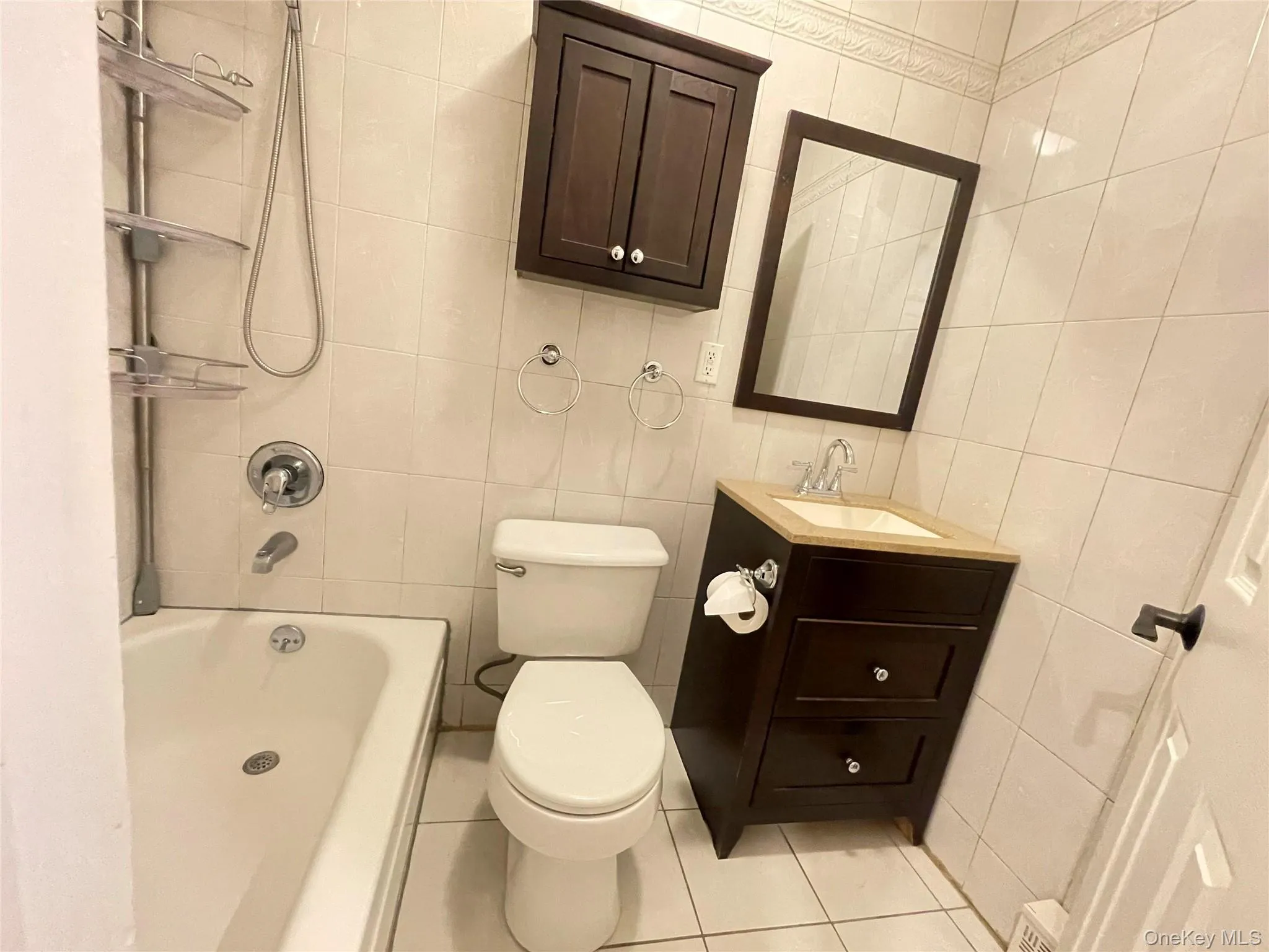 Bathroom featuring vanity, tile walls, light tile patterned floors, and bathtub / shower combination Bathroom featuring vanity, tile walls, light tile patterned floors, and bathtub / shower combination