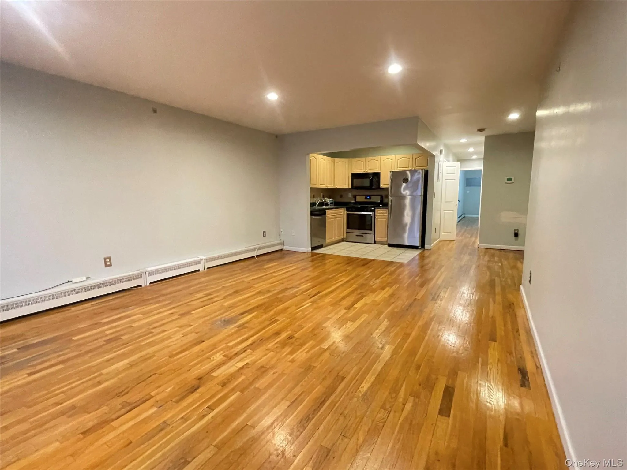 Unfurnished living room featuring a baseboard radiator, light wood-style flooring, and recessed lighting Unfurnished living room featuring a baseboard radiator, light wood-style flooring, and recessed lighting
