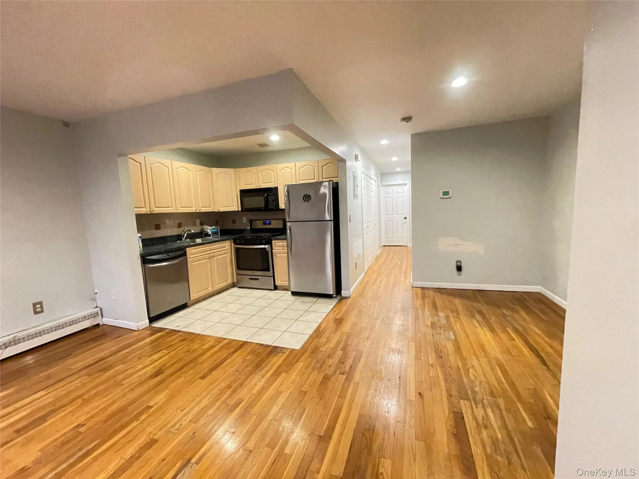Kitchen featuring light wood-style floors, appliances with stainless steel finishes, dark countertops, recessed lighting, and open floor plan Kitchen featuring light wood-style floors, appliances with stainless steel finishes, dark countertops, recessed lighting, and open floor plan