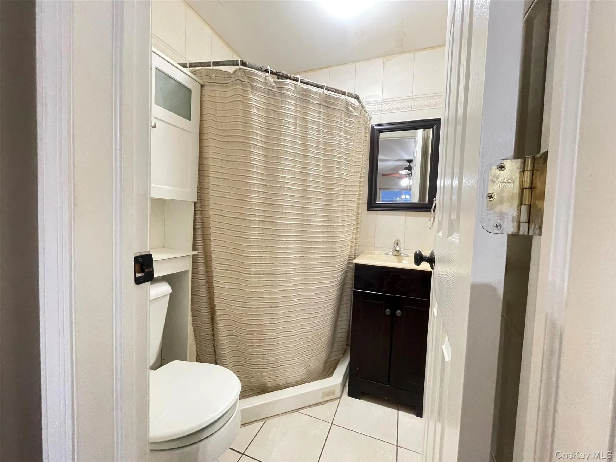 Full bath with a shower stall, vanity, and light tile patterned flooring Full bath with a shower stall, vanity, and light tile patterned flooring