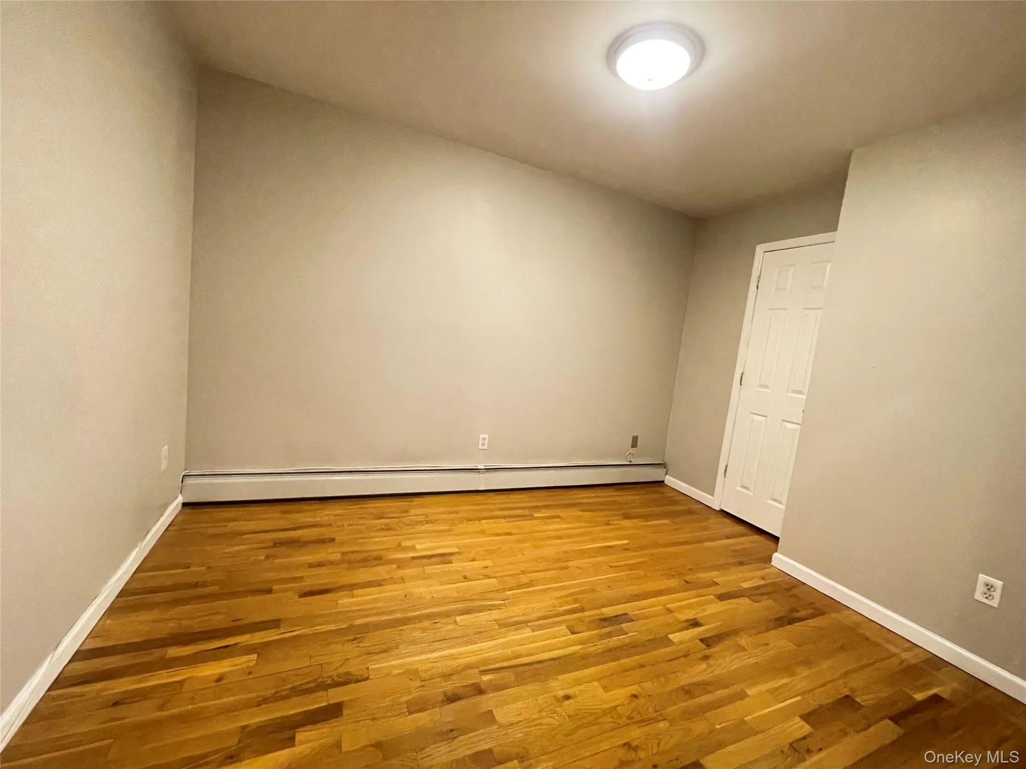 Spare room with light wood-style floors and a baseboard radiator Spare room with light wood-style floors and a baseboard radiator