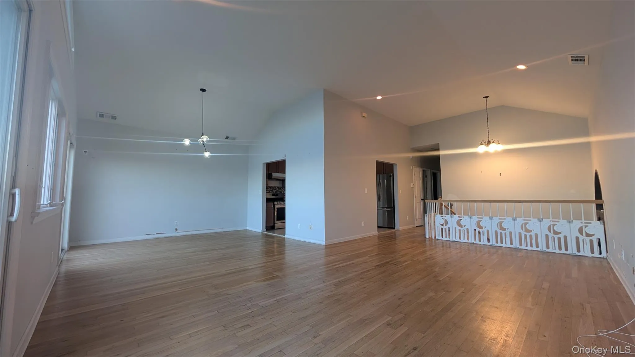 Spare room with a chandelier, light wood-style floors, a fireplace, high vaulted ceiling, and recessed lighting Spare room with a chandelier, light wood-style floors, a fireplace, high vaulted ceiling, and recessed lighting