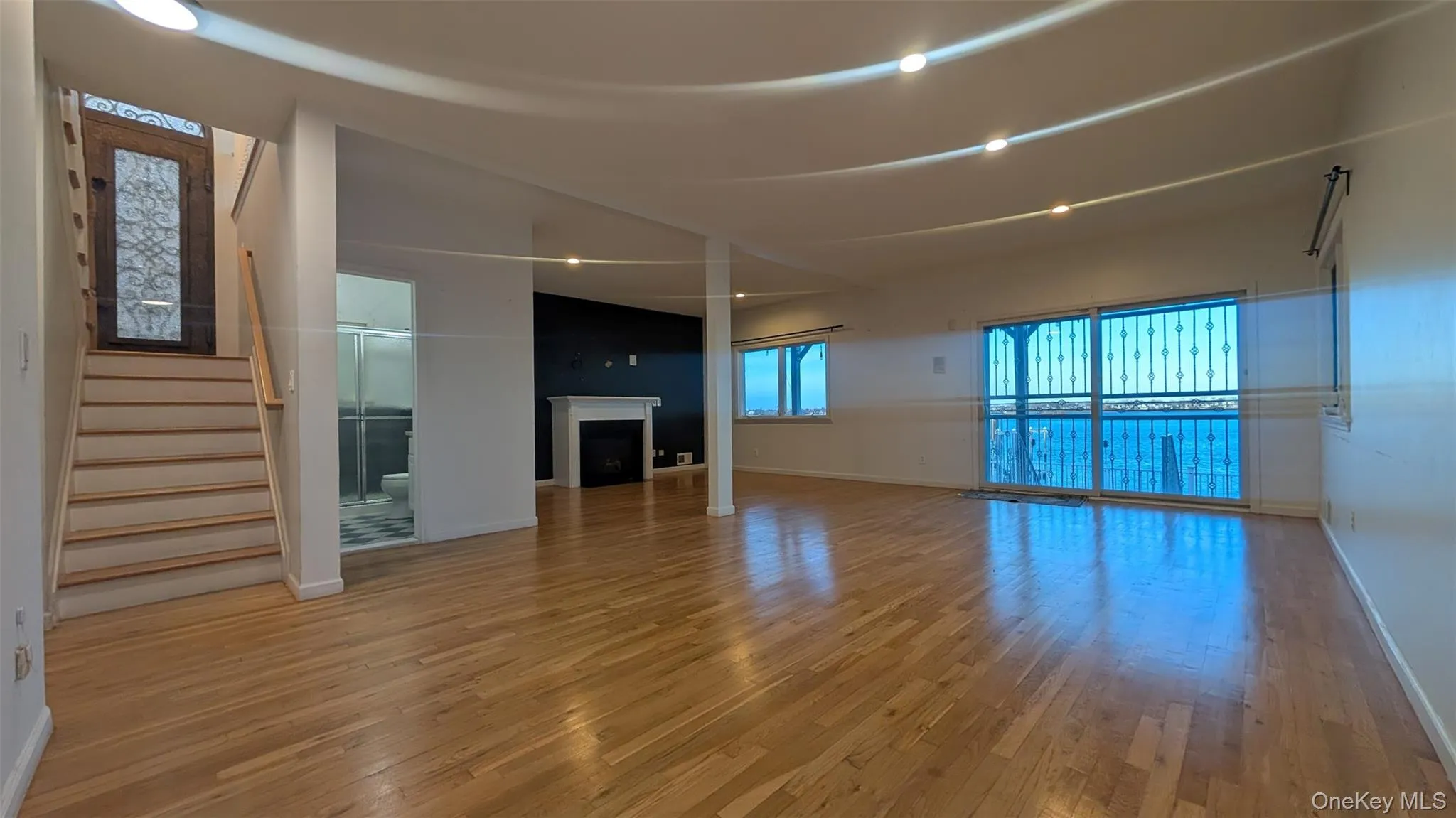 Unfurnished living room with hardwood / wood-style flooring, a fireplace, and stairs Unfurnished living room with hardwood / wood-style flooring, a fireplace, and stairs
