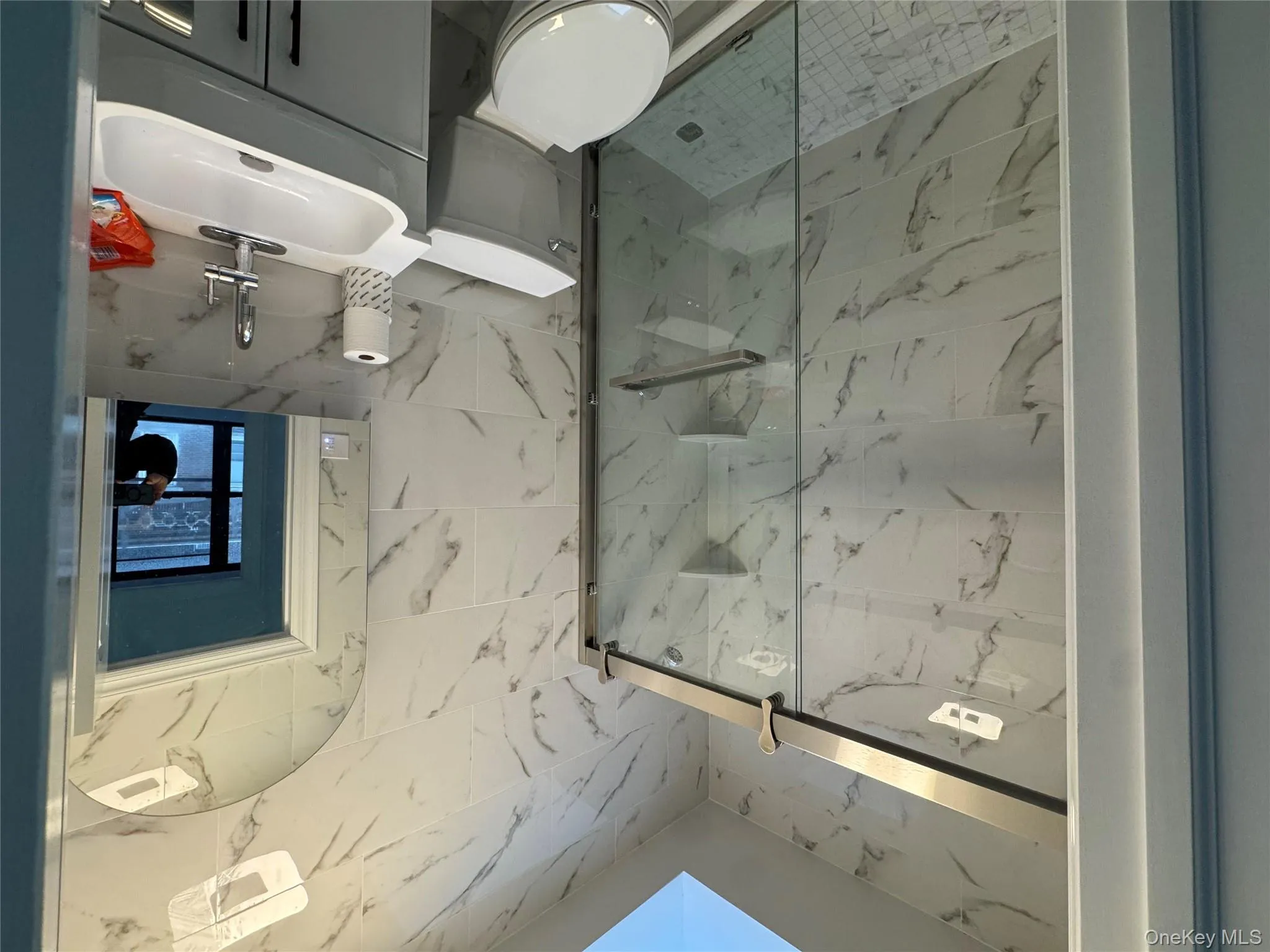 Bathroom with tile walls, vanity, a marble finish shower, and a skylight Bathroom with tile walls, vanity, a marble finish shower, and a skylight