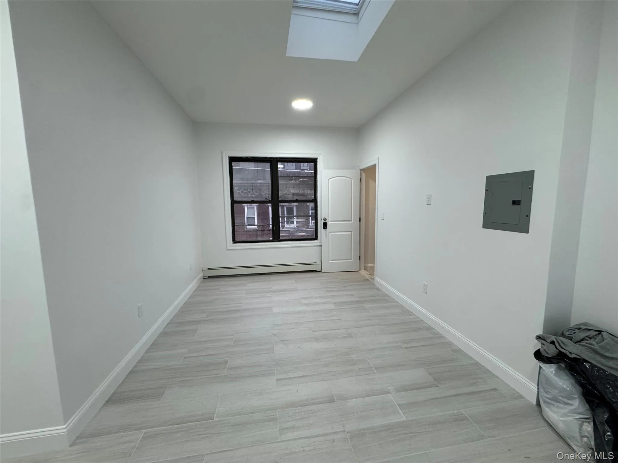 Hallway featuring a skylight, electric panel, a baseboard heating unit, wood tiled floors, and recessed lighting Hallway featuring a skylight, electric panel, a baseboard heating unit, wood tiled floors, and recessed lighting