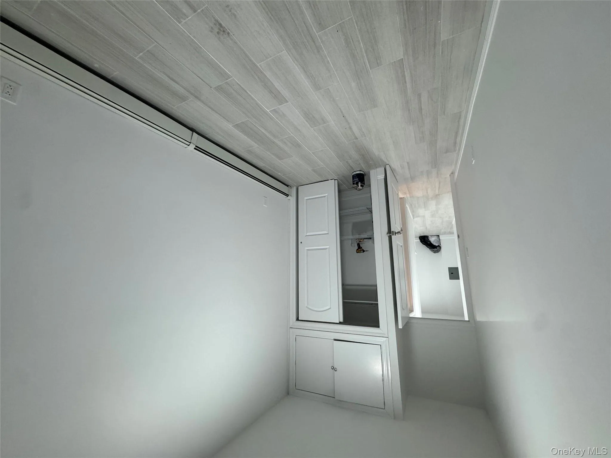 Unfurnished bedroom featuring a baseboard heating unit, wood tiled floors, and a closet Unfurnished bedroom featuring a baseboard heating unit, wood tiled floors, and a closet