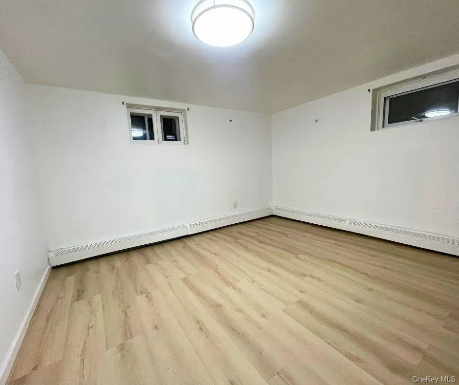 Unfurnished room featuring a baseboard heating unit and light wood finished floors Unfurnished room featuring a baseboard heating unit and light wood finished floors