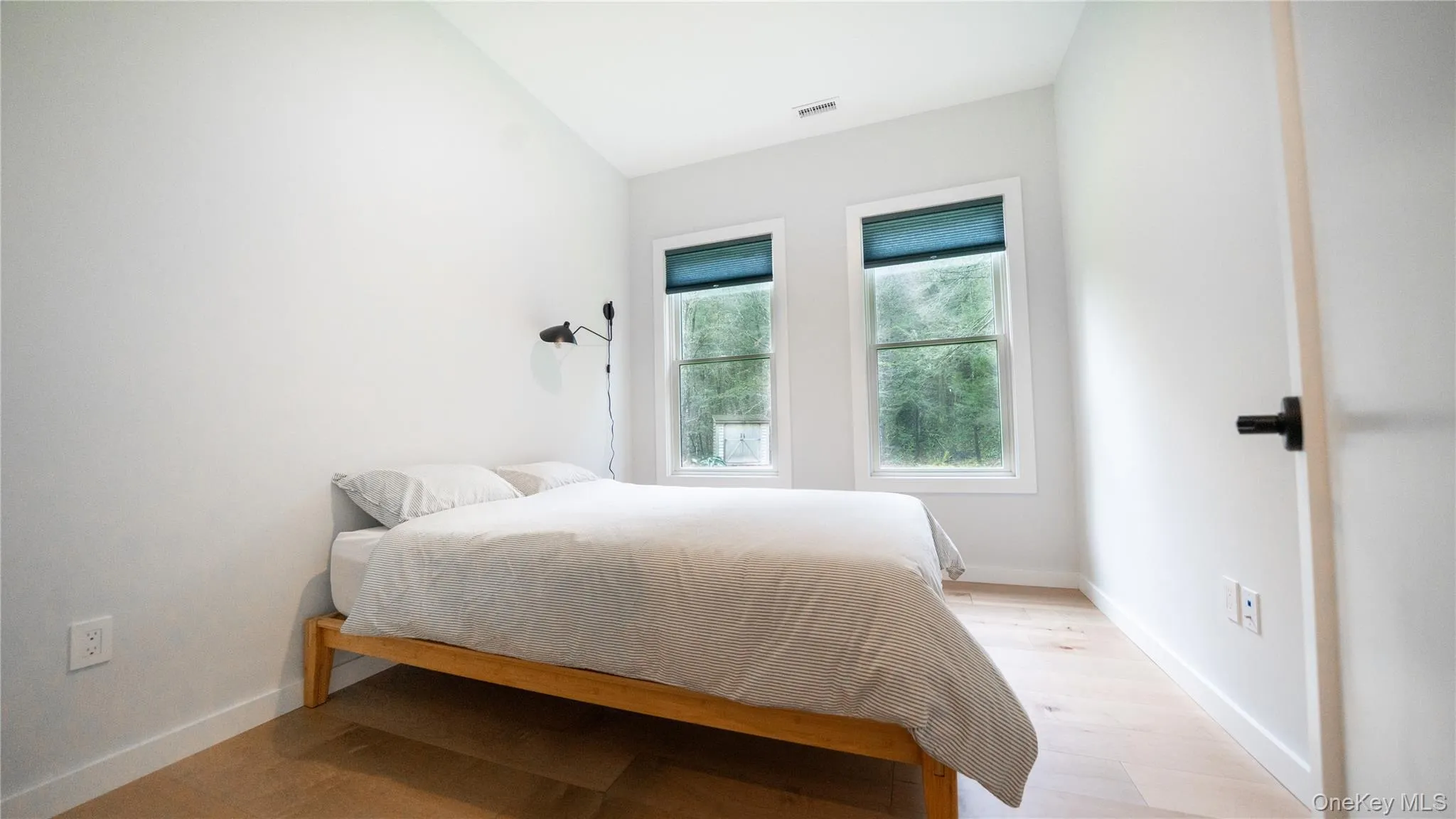 Bedroom featuring light wood-style flooring and vaulted ceiling Bedroom featuring light wood-style flooring and vaulted ceiling