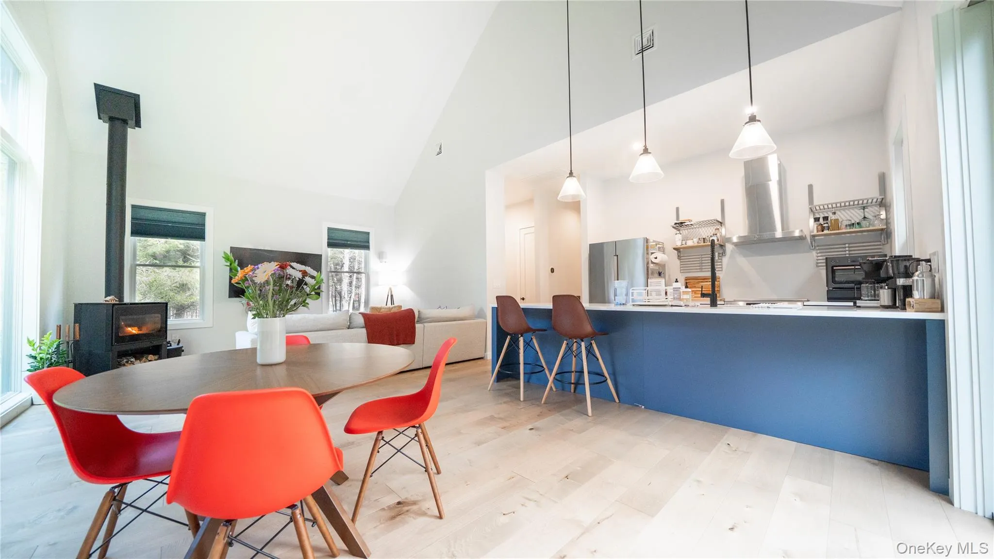 Dining area with a wood stove, high vaulted ceiling, and light wood-style floors Dining area with a wood stove, high vaulted ceiling, and light wood-style floors