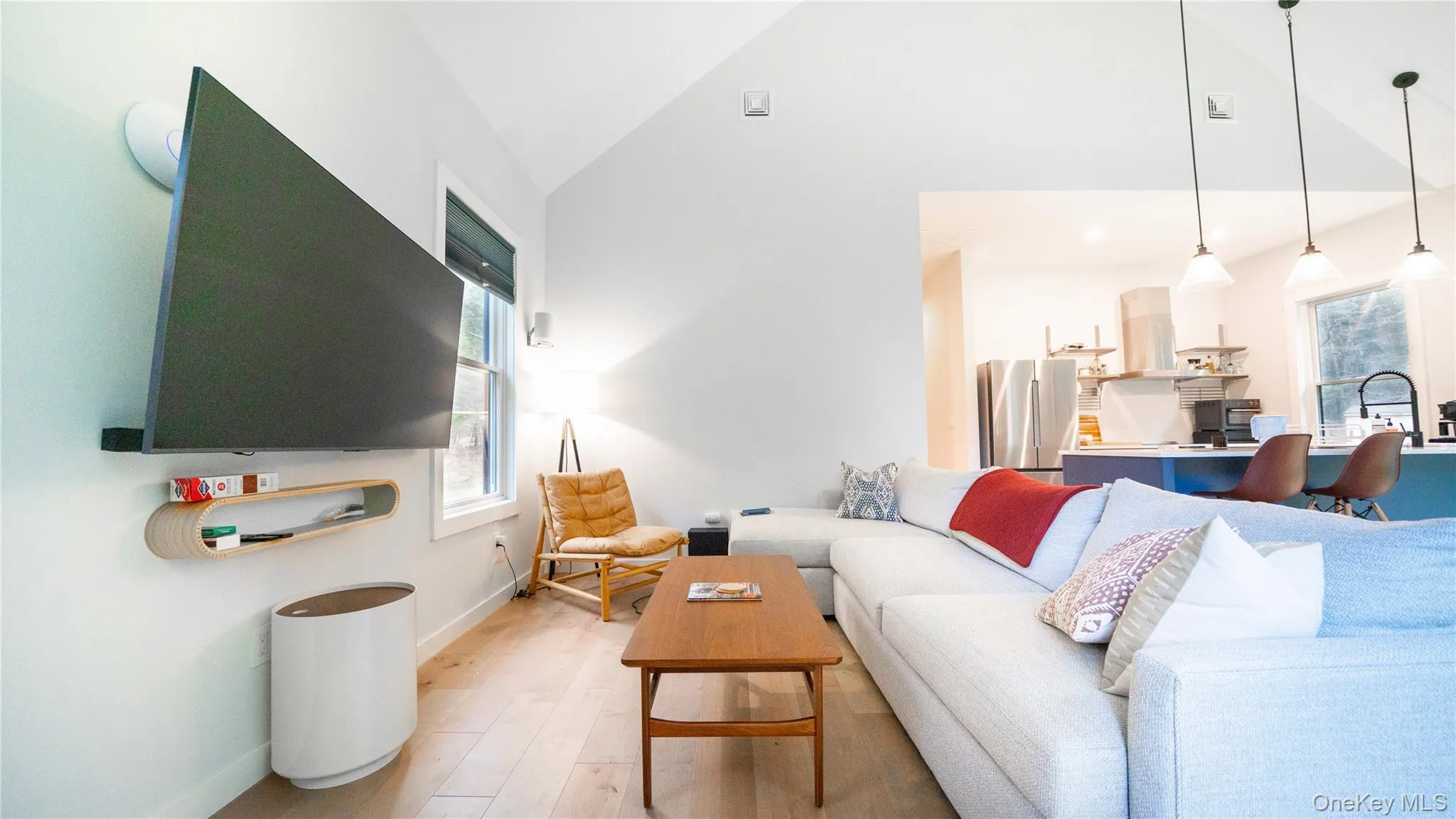 Living area featuring light wood-style floors and high vaulted ceiling Living area featuring light wood-style floors and high vaulted ceiling