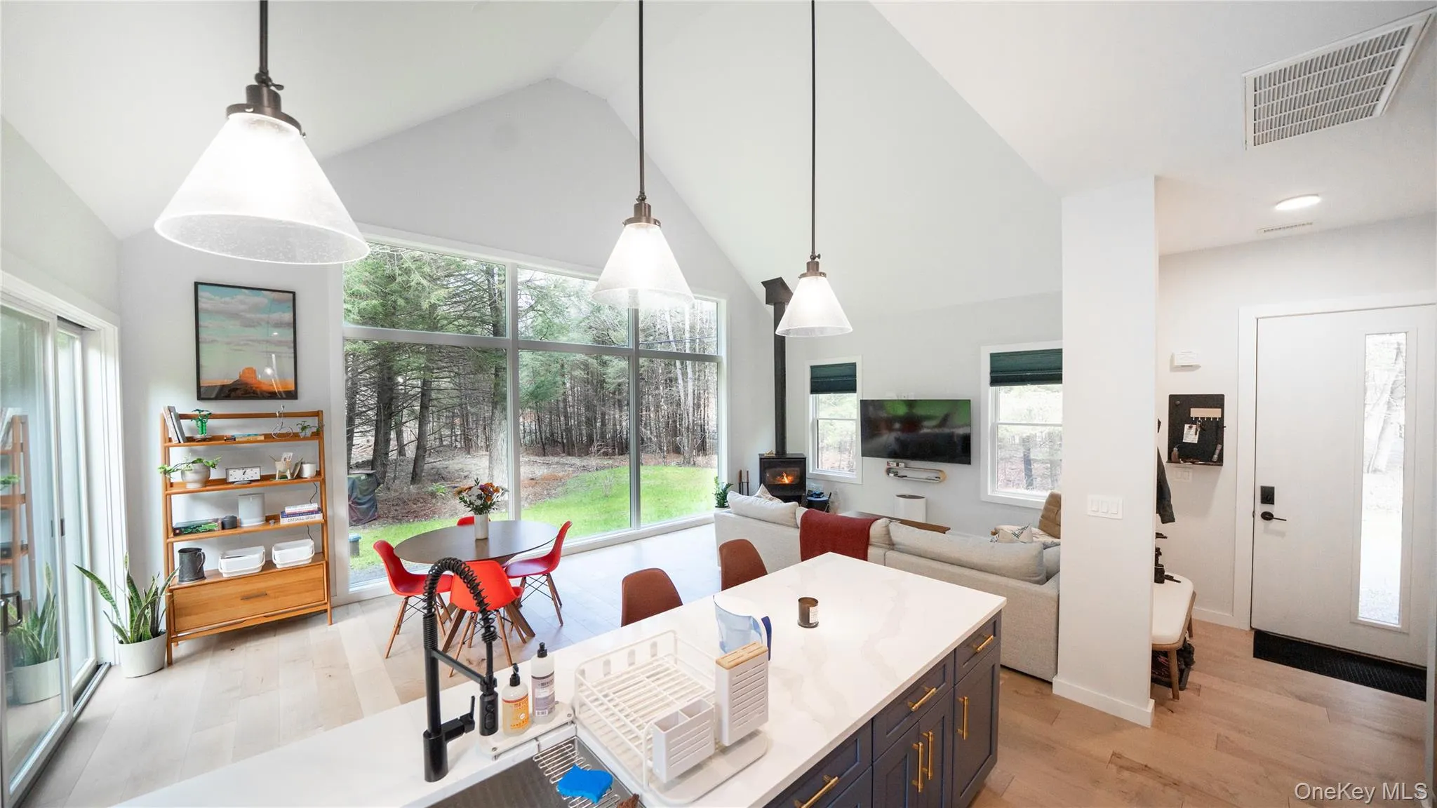 Kitchen with high vaulted ceiling, pendant lighting, light stone counters, light wood-style floors, and open floor plan Kitchen with high vaulted ceiling, pendant lighting, light stone counters, light wood-style floors, and open floor plan