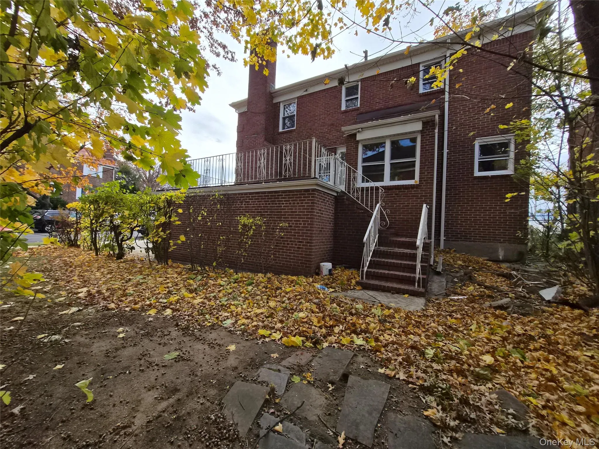 Back of house featuring a chimney, a wooden deck, brick siding, and stairs Back of house featuring a chimney, a wooden deck, brick siding, and stairs