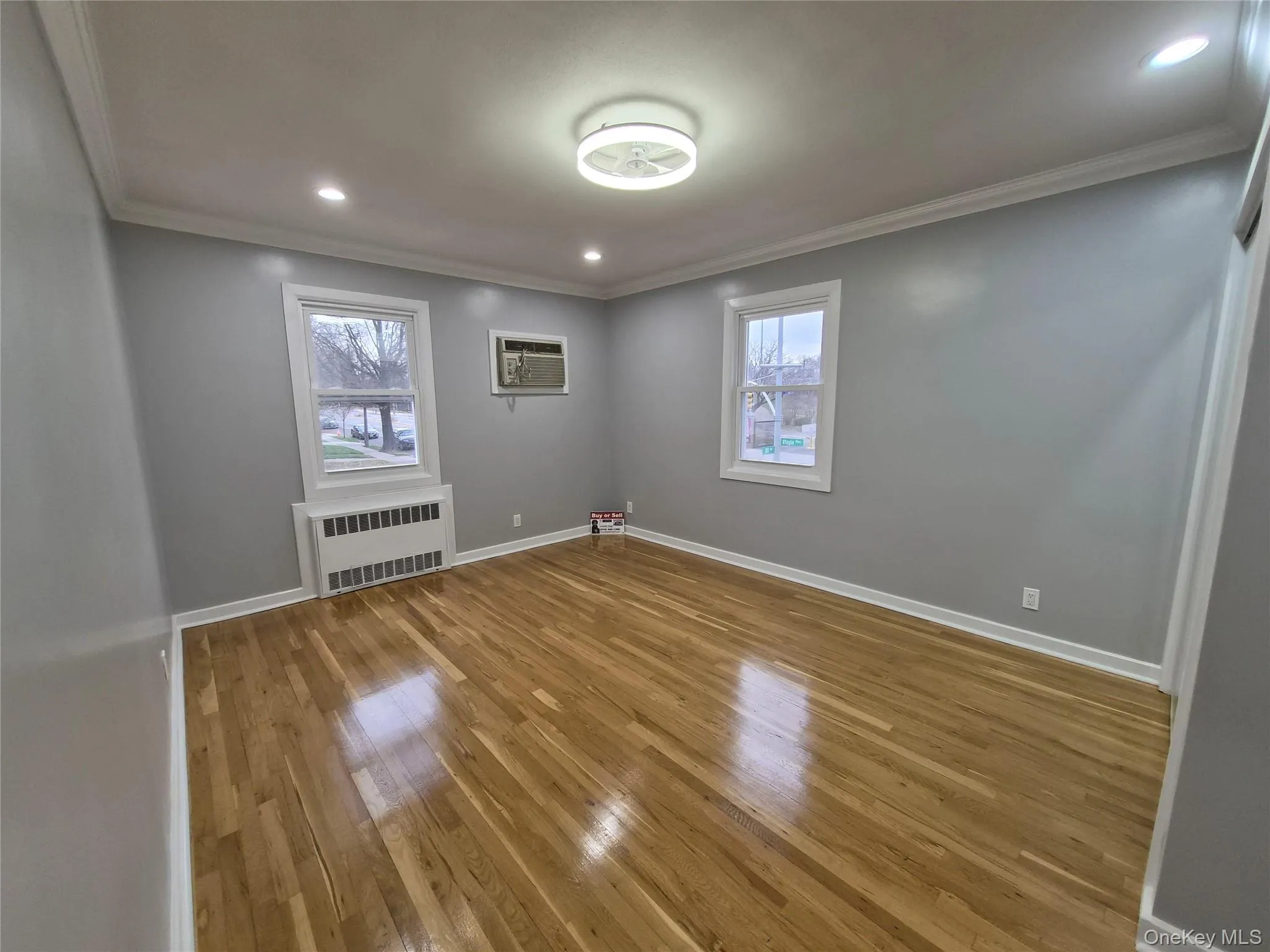 Spare room featuring recessed lighting, crown molding, light wood-type flooring, radiator, and a wall unit AC Spare room featuring recessed lighting, crown molding, light wood-type flooring, radiator, and a wall unit AC