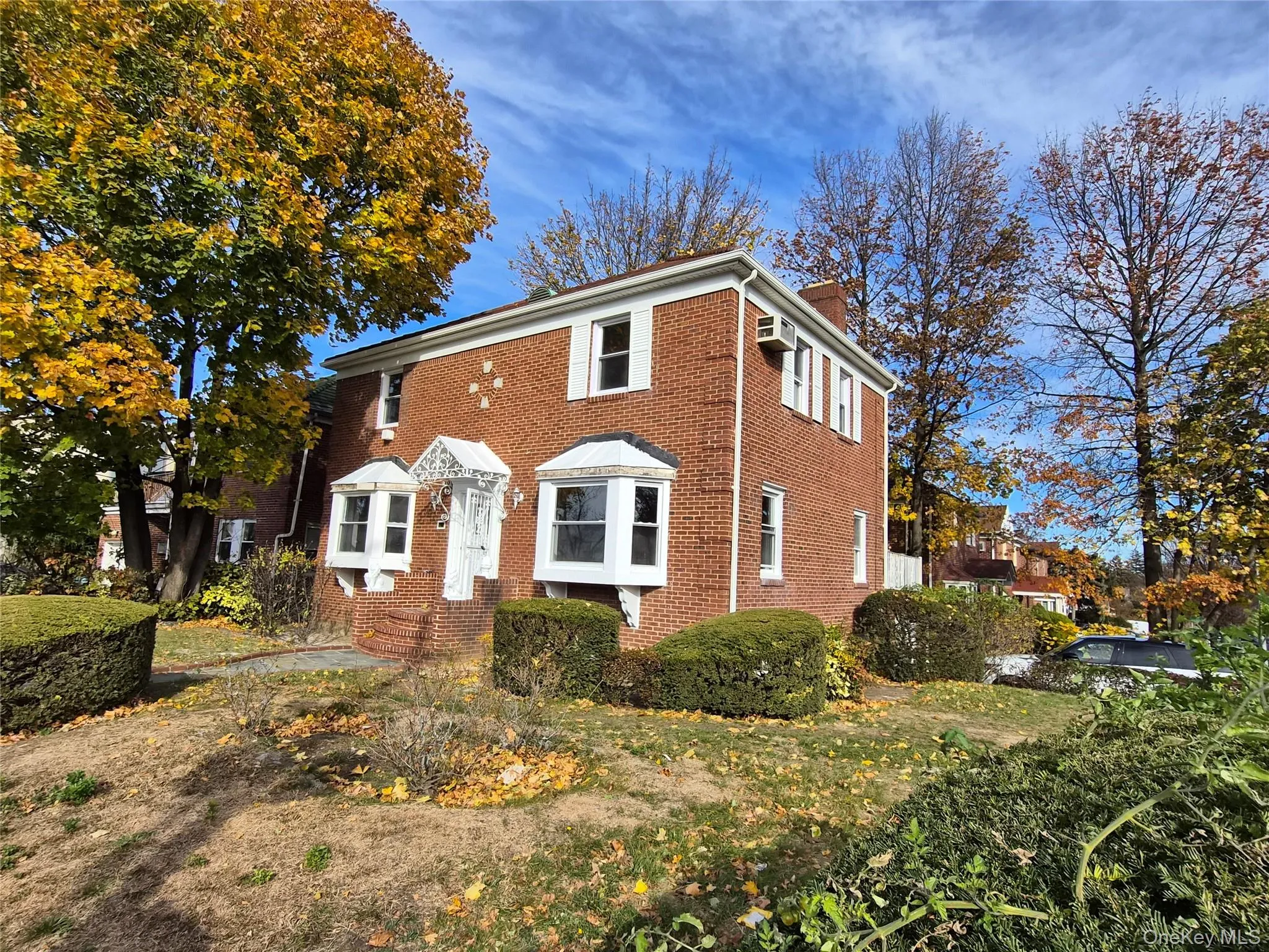 Colonial house featuring a chimney and brick siding Colonial house featuring a chimney and brick siding