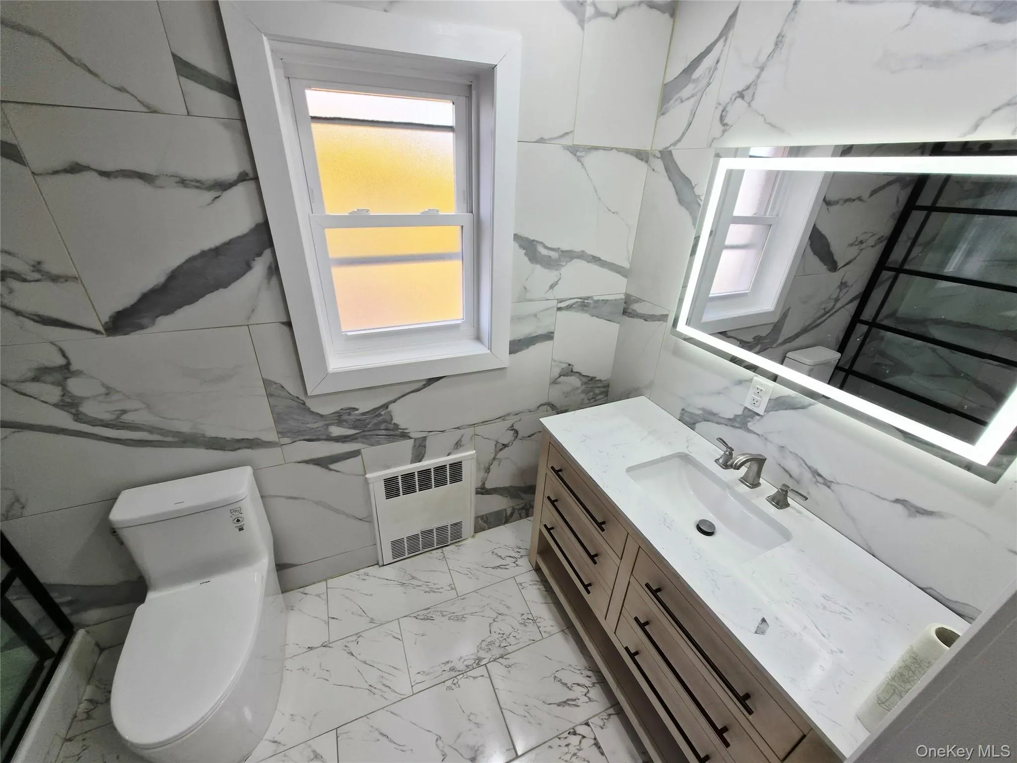 Bathroom featuring vanity, radiator heating unit, and light marble finish flooring Bathroom featuring vanity, radiator heating unit, and light marble finish flooring