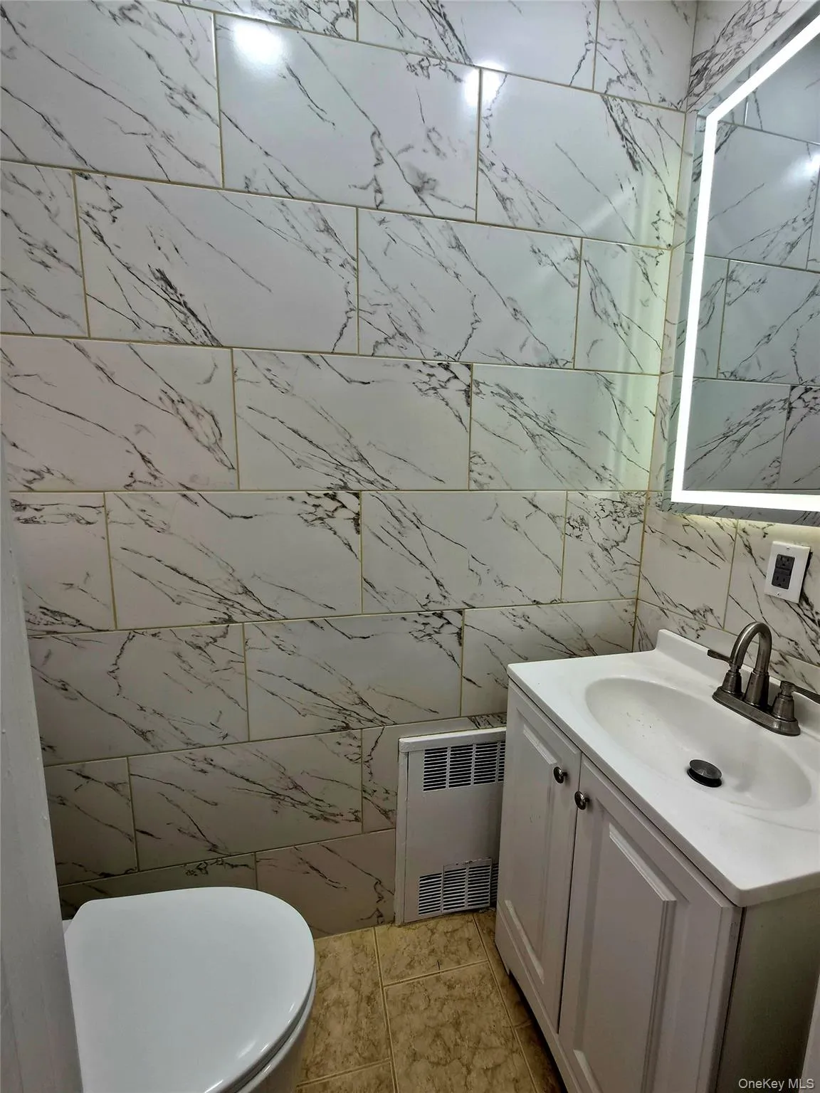 Bathroom with tile walls, vanity, and radiator Bathroom with tile walls, vanity, and radiator