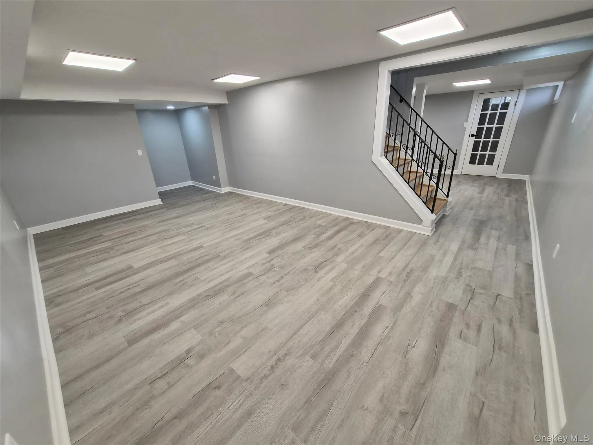 Finished below grade area featuring stairway and light wood-style floors Finished below grade area featuring stairway and light wood-style floors