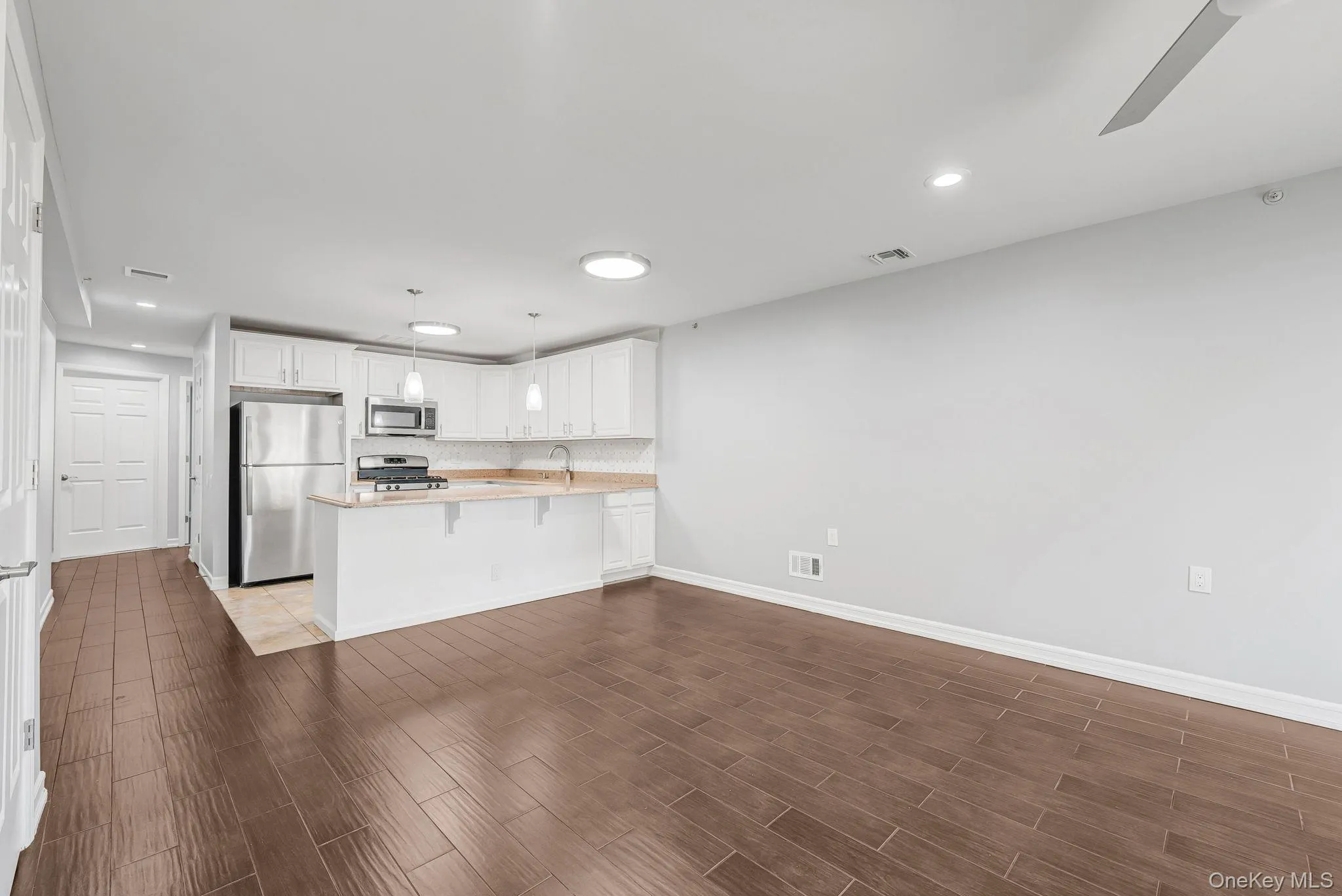 Kitchen with white cabinets, appliances with stainless steel finishes, recessed lighting, hanging light fixtures, and wood tiled floors Kitchen with white cabinets, appliances with stainless steel finishes, recessed lighting, hanging light fixtures, and wood tiled floors