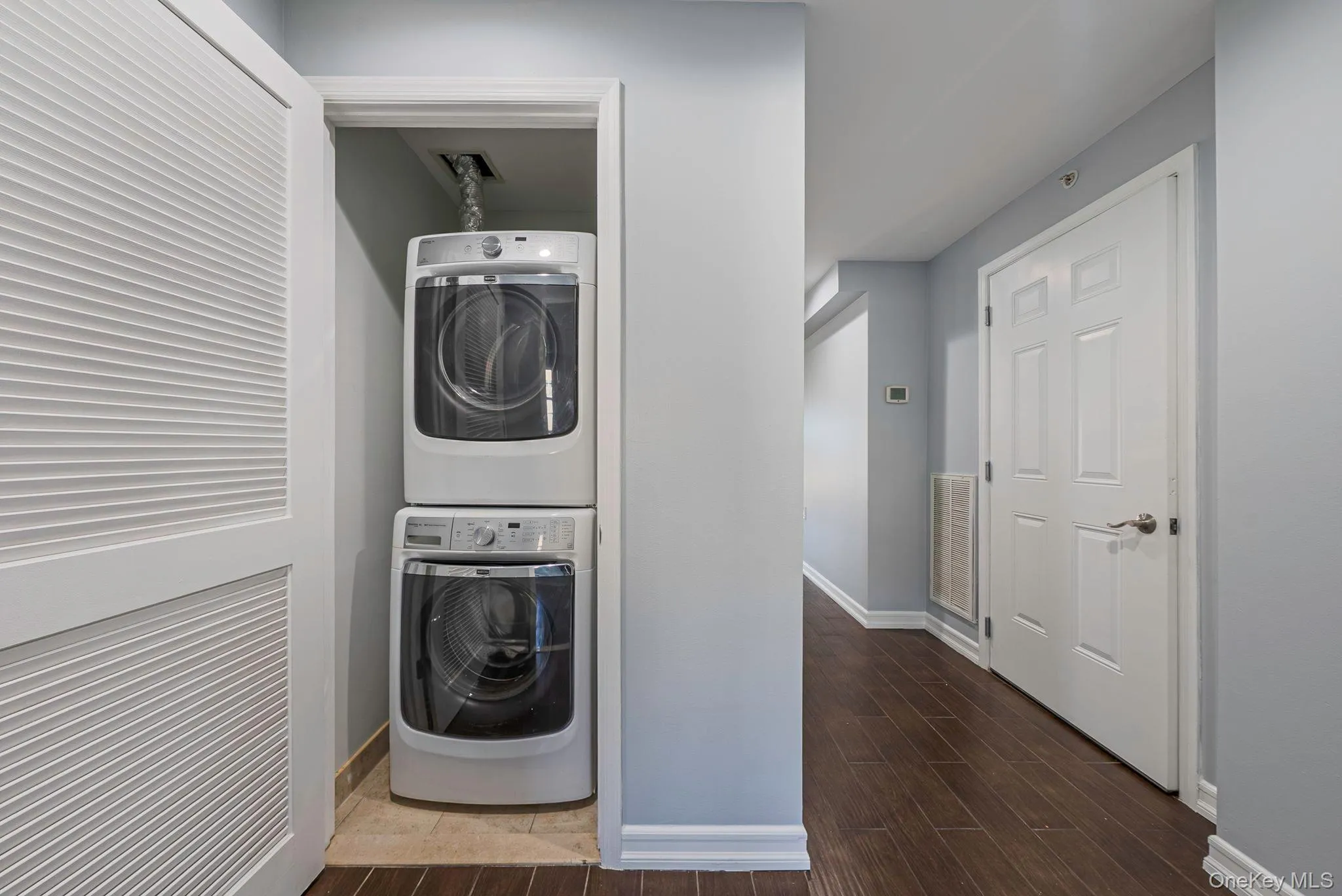 Washroom with stacked washer / dryer and wood tiled floors Washroom with stacked washer / dryer and wood tiled floors