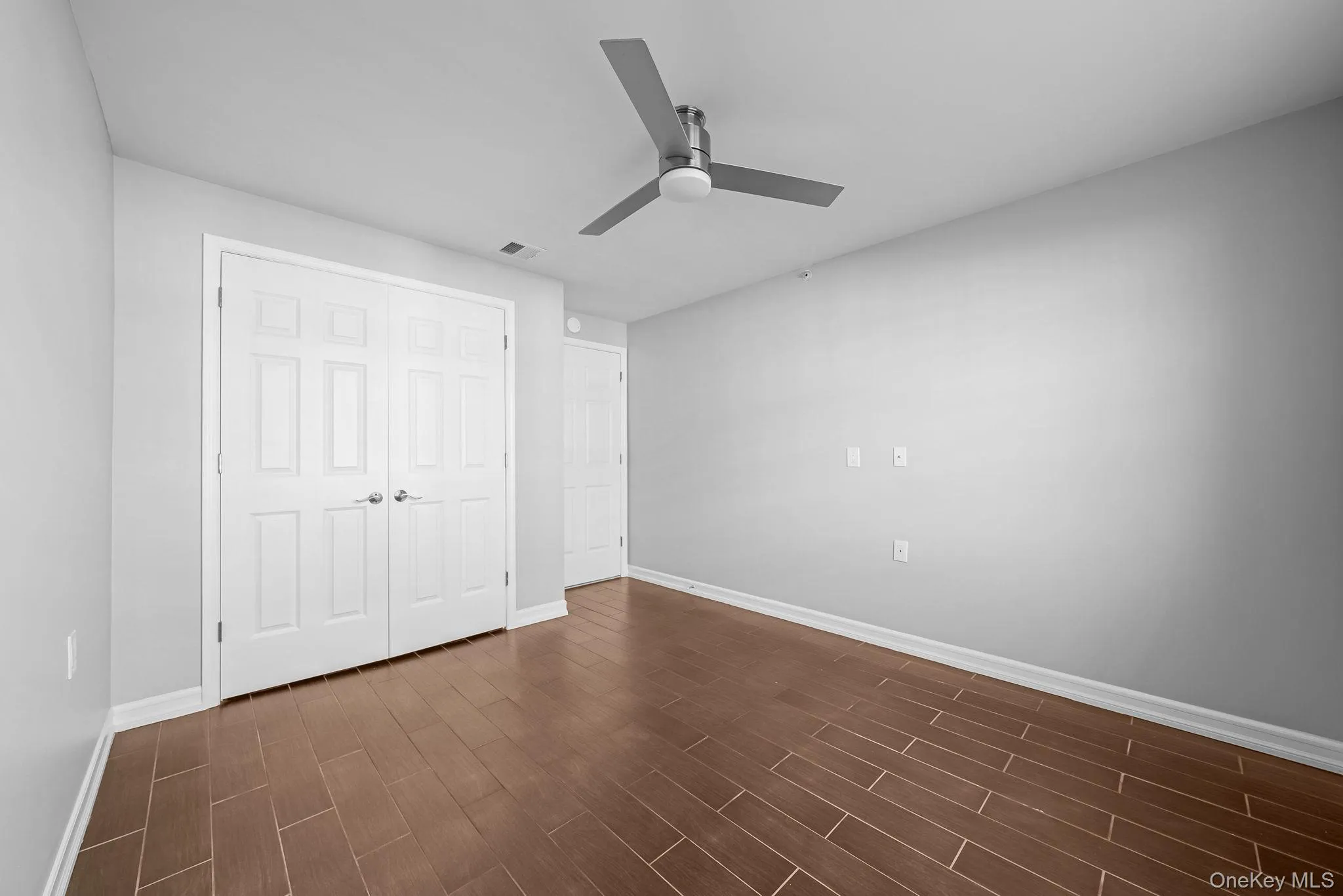 Unfurnished bedroom featuring dark wood-type flooring, a ceiling fan, and a closet Unfurnished bedroom featuring dark wood-type flooring, a ceiling fan, and a closet