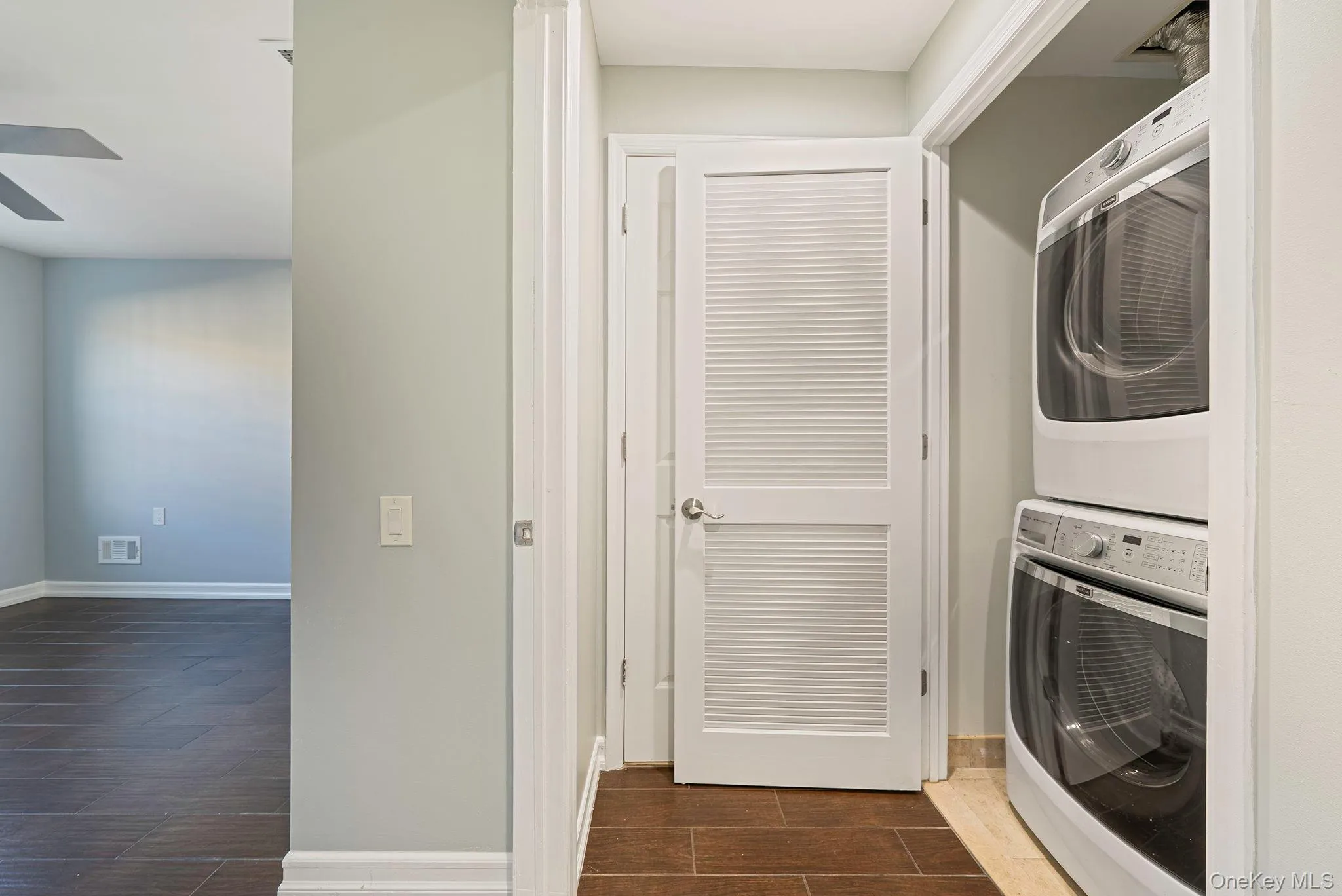 Laundry area featuring wood tiled floors, stacked washer / drying machine, and ceiling fan Laundry area featuring wood tiled floors, stacked washer / drying machine, and ceiling fan