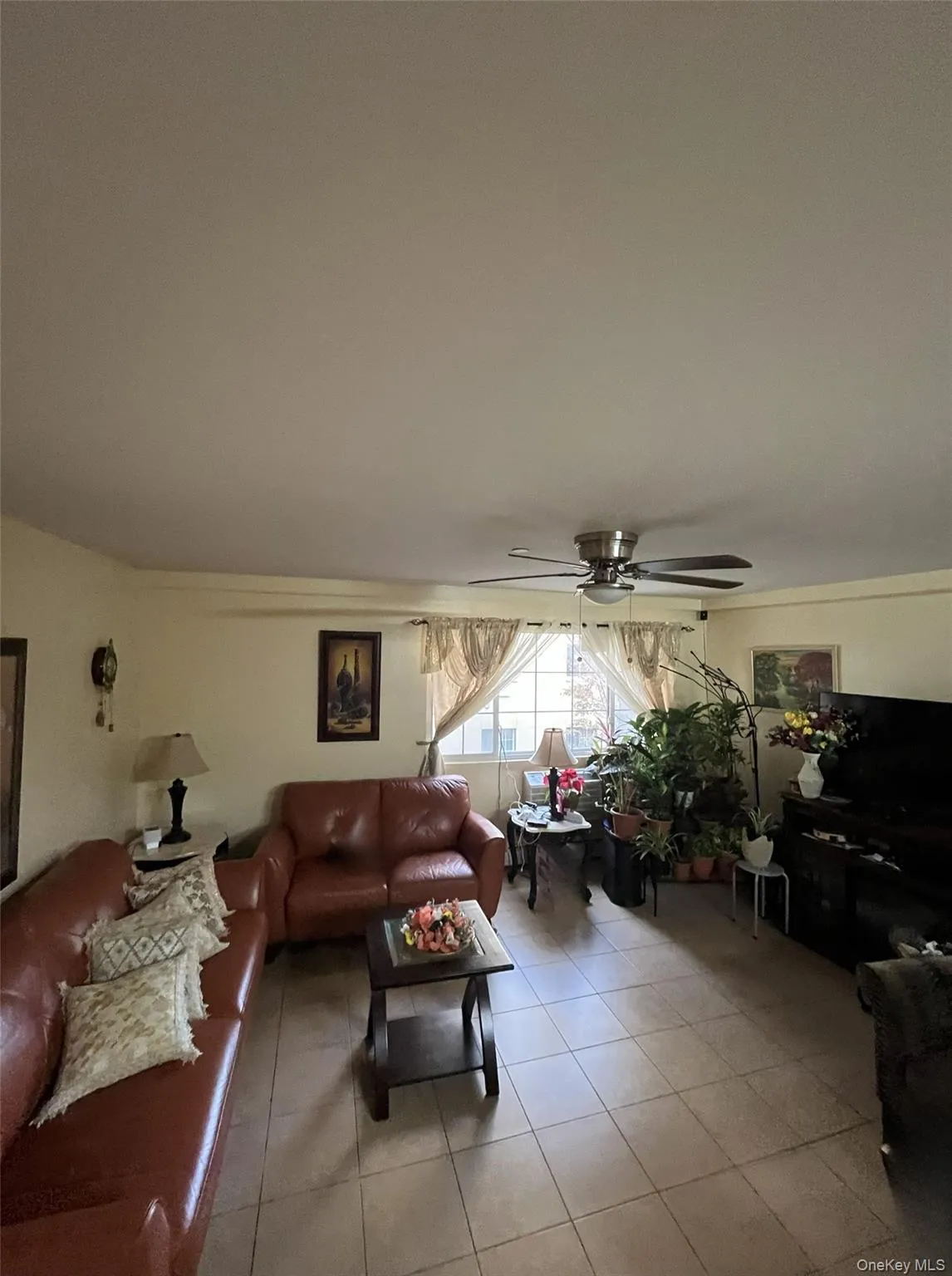 Living room featuring light tile patterned flooring and a ceiling fan Living room featuring light tile patterned flooring and a ceiling fan