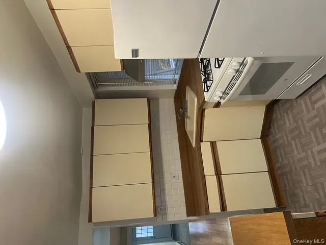 Kitchen featuring fridge, stove, decorative backsplash, ventilation hood, and white cabinetry Kitchen featuring fridge, stove, decorative backsplash, ventilation hood, and white cabinetry