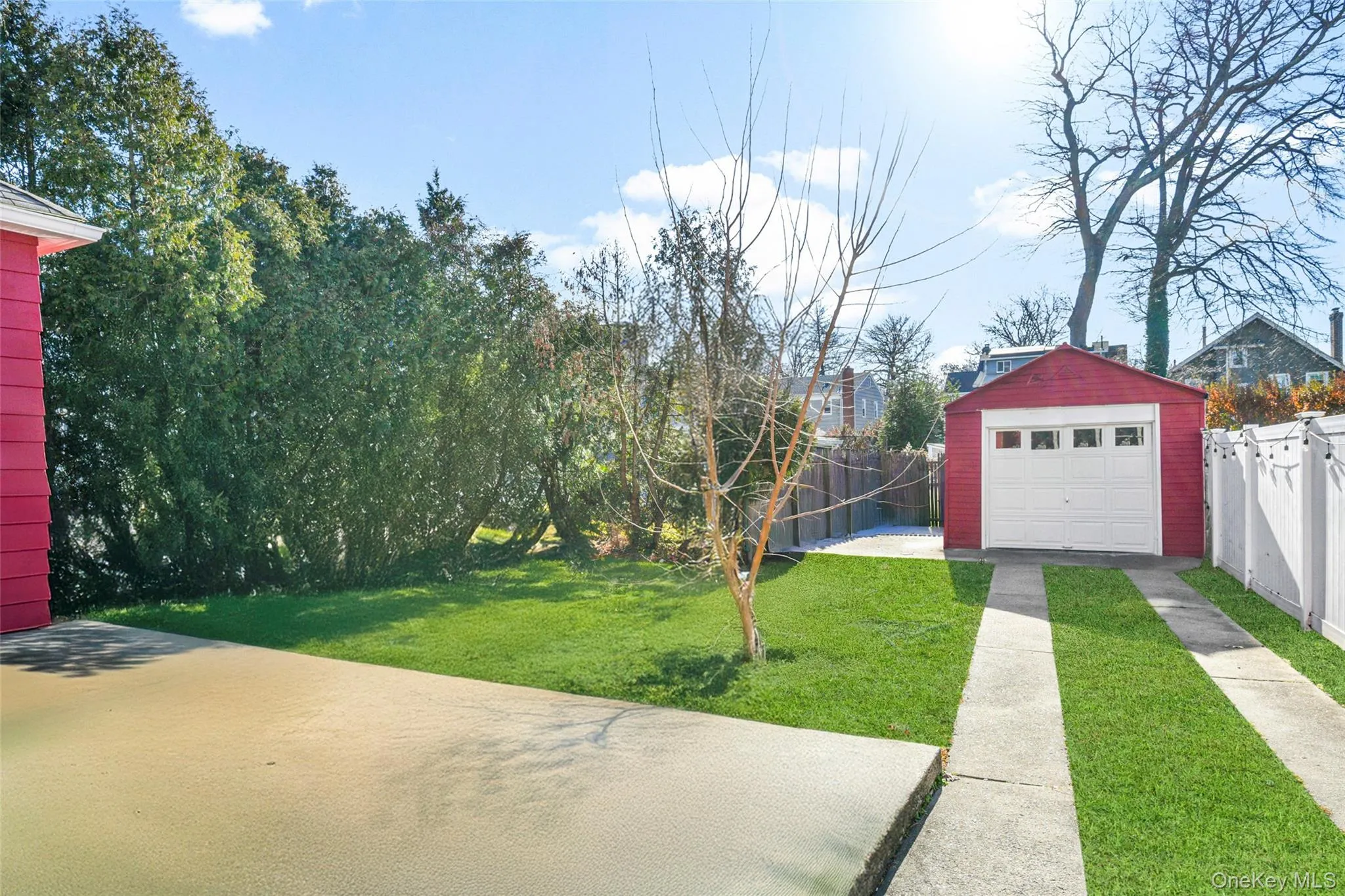 Fenced backyard featuring an outdoor structure and driveway Fenced backyard featuring an outdoor structure and driveway