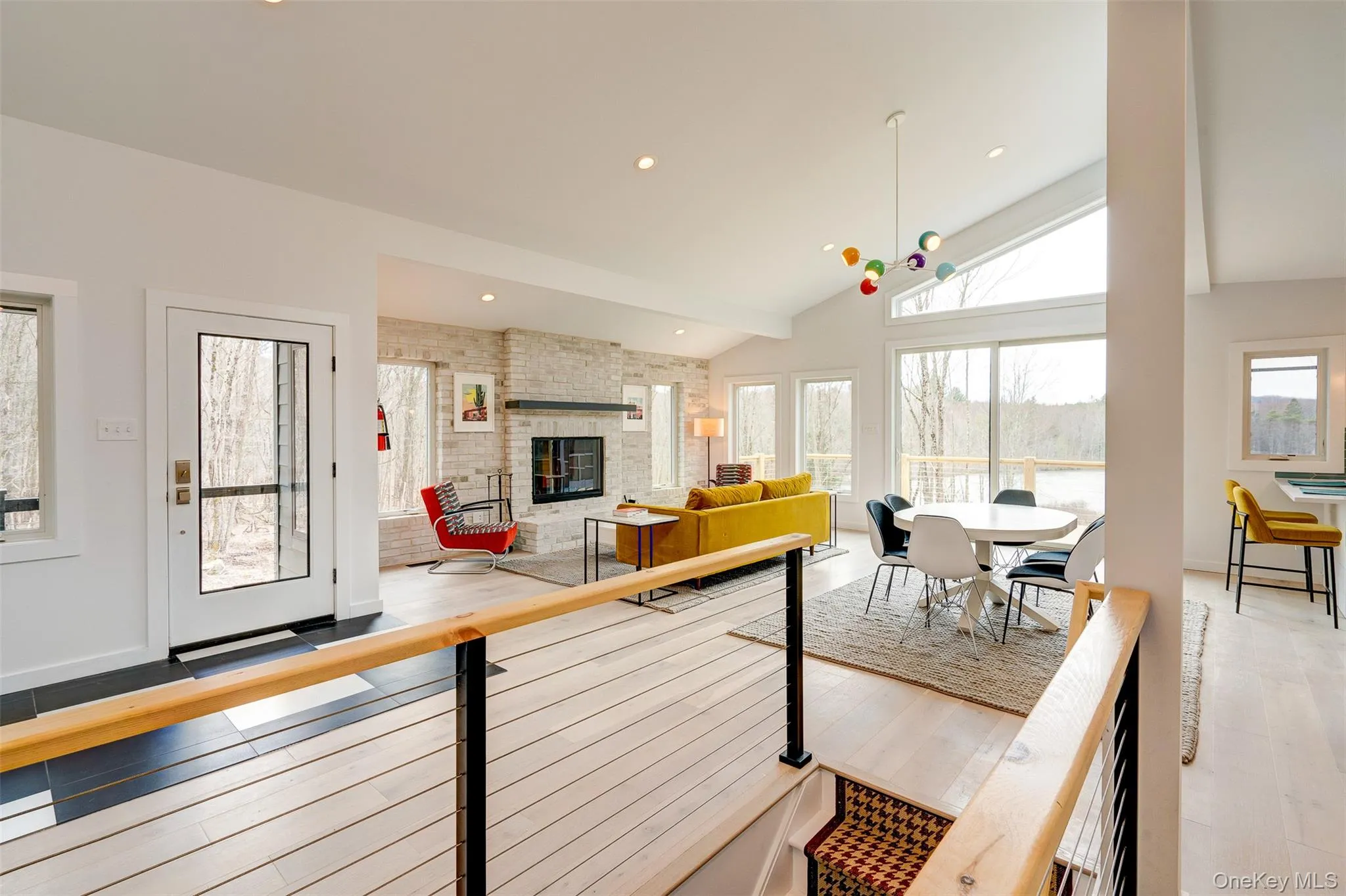 Living room with a fireplace, light wood-type flooring, high vaulted ceiling, and recessed lighting Living room with a fireplace, light wood-type flooring, high vaulted ceiling, and recessed lighting