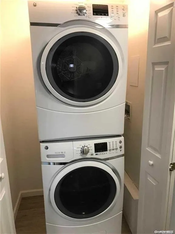 Laundry room featuring stacked washer and clothes dryer and wood finished floors Laundry room featuring stacked washer and clothes dryer and wood finished floors