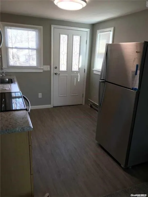 Kitchen featuring freestanding refrigerator, dark wood-type flooring, electric range, and light countertops Kitchen featuring freestanding refrigerator, dark wood-type flooring, electric range, and light countertops