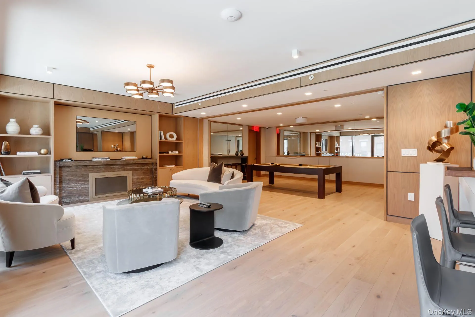 Lounge with light wood-style floors, built in shelves, a fireplace, a chandelier, and recessed lighting Lounge with light wood-style floors, built in shelves, a fireplace, a chandelier, and recessed lighting