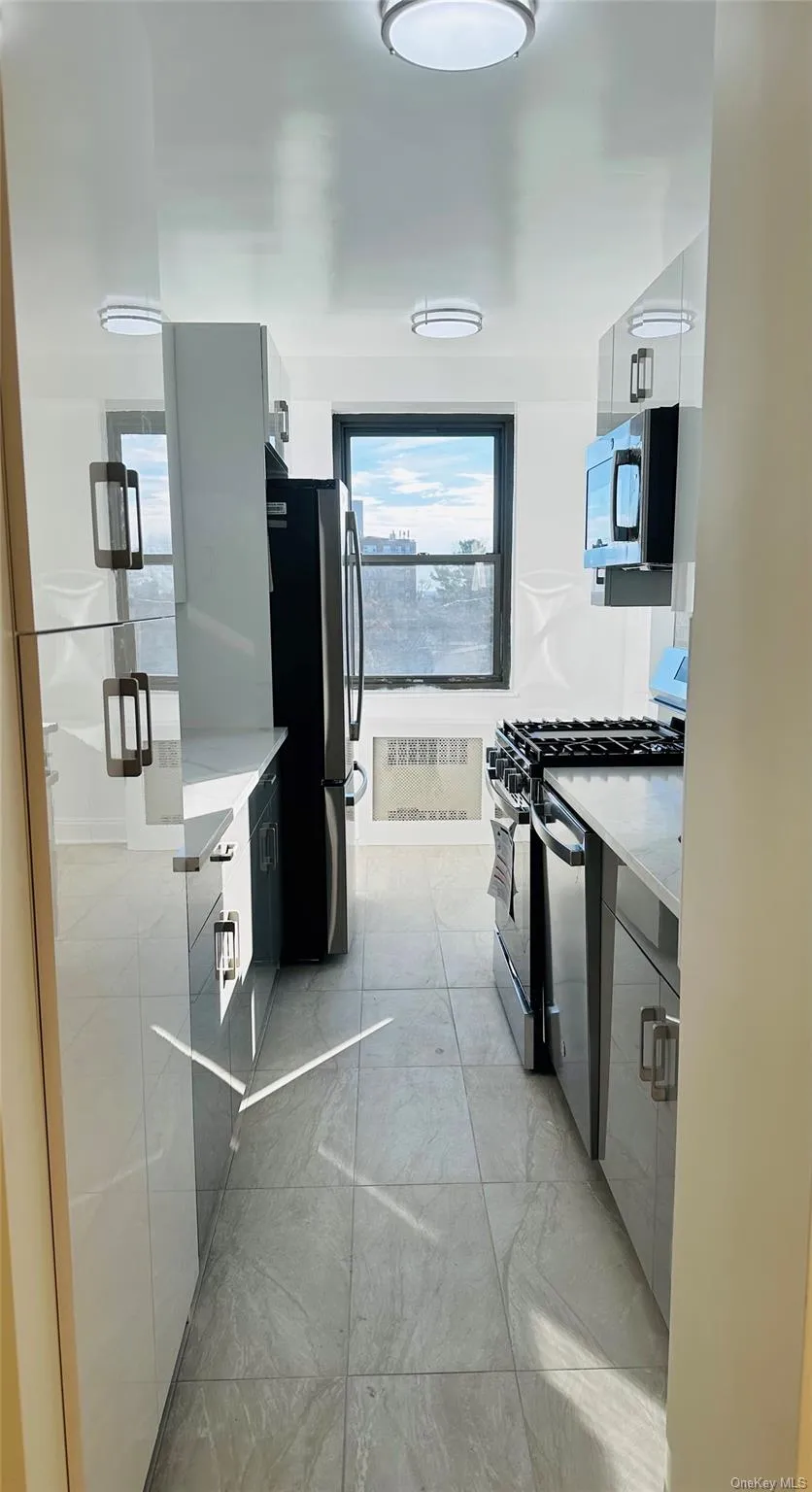 Kitchen with appliances with stainless steel finishes, light stone countertops, and modern cabinets Kitchen with appliances with stainless steel finishes, light stone countertops, and modern cabinets