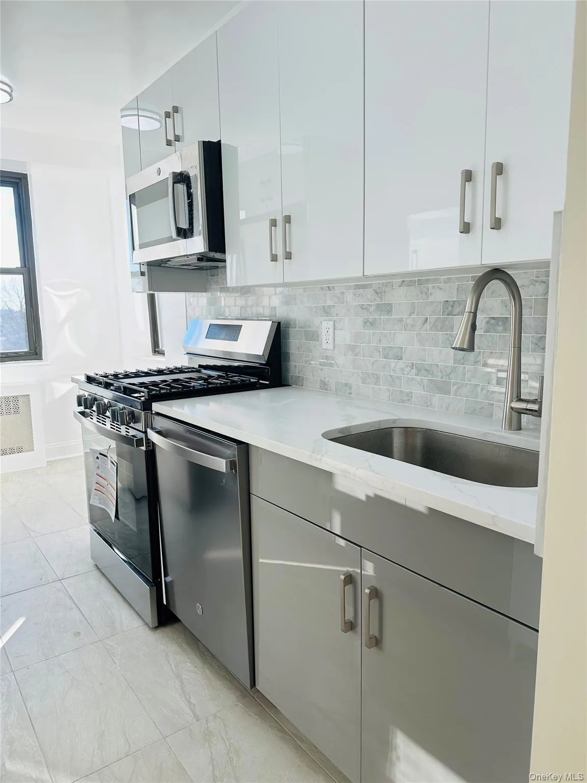 Kitchen featuring appliances with stainless steel finishes, decorative backsplash, modern cabinets, light stone counters, and white cabinets Kitchen featuring appliances with stainless steel finishes, decorative backsplash, modern cabinets, light stone counters, and white cabinets