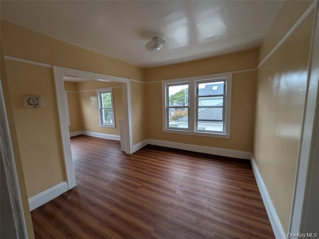 Empty room featuring dark wood-type flooring and baseboards Empty room featuring dark wood-type flooring and baseboards