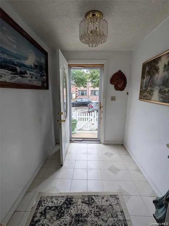 Doorway with a textured ceiling, a chandelier, and tile patterned flooring Doorway with a textured ceiling, a chandelier, and tile patterned flooring