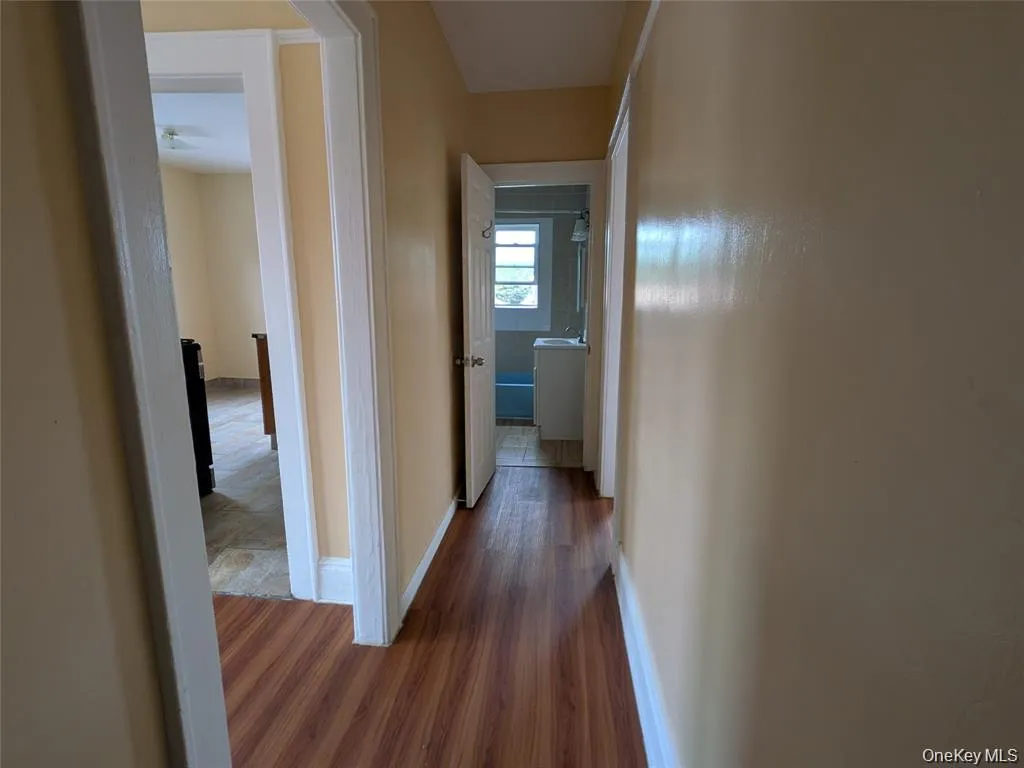 Corridor with dark wood-type flooring and baseboards Corridor with dark wood-type flooring and baseboards