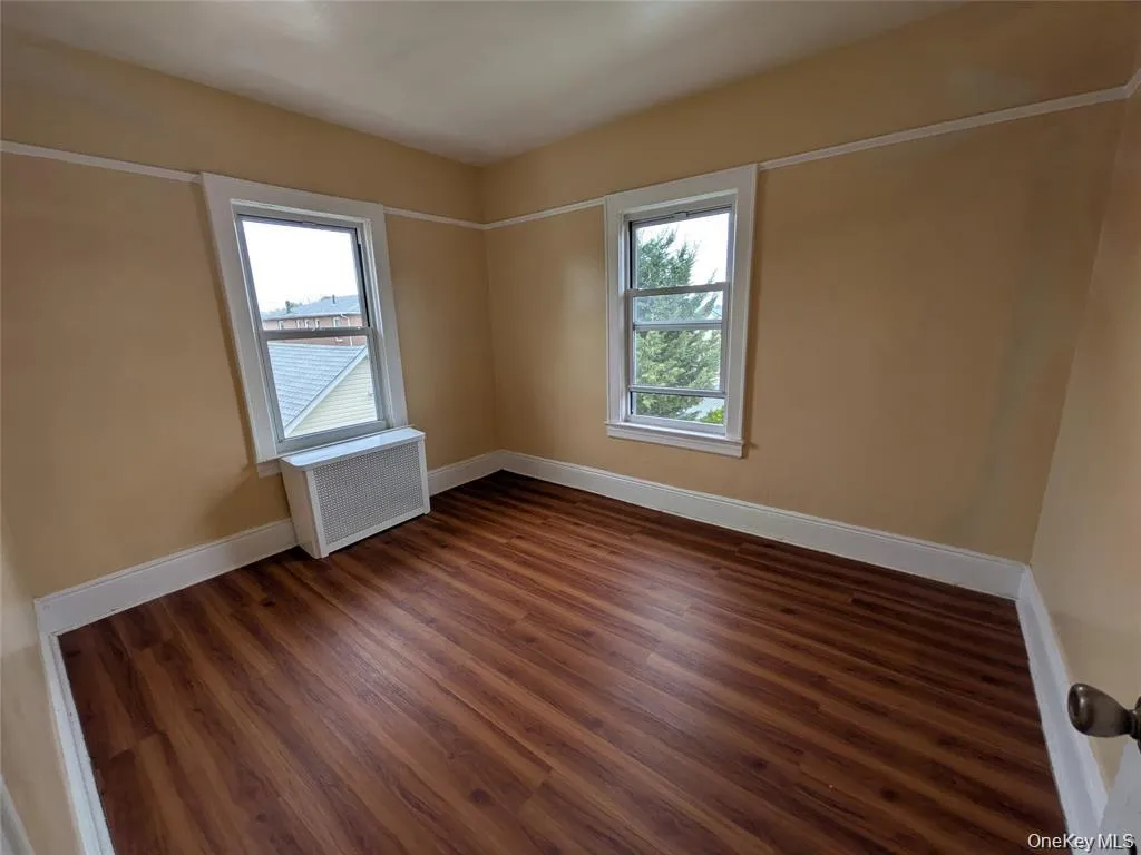 Unfurnished room with radiator heating unit and dark wood-type flooring Unfurnished room with radiator heating unit and dark wood-type flooring